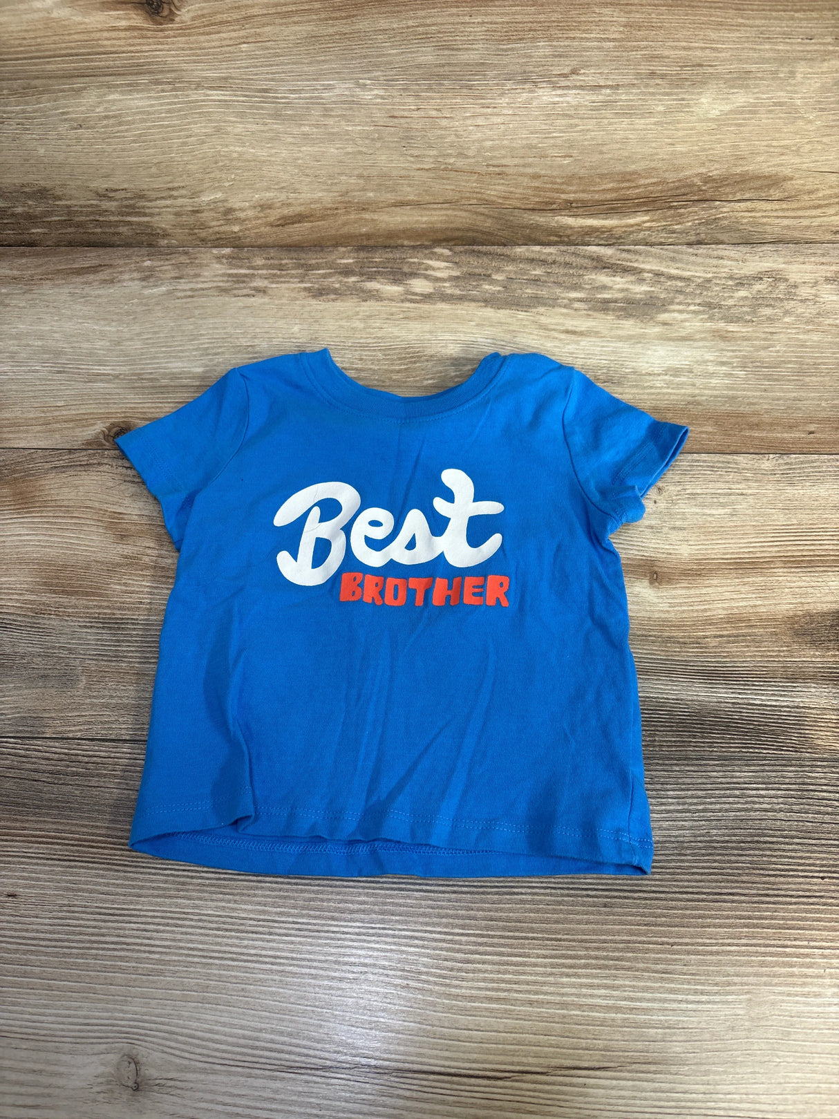 Blue toddler t-shirt with white and red text reading 'Best Brother' on wooden floor