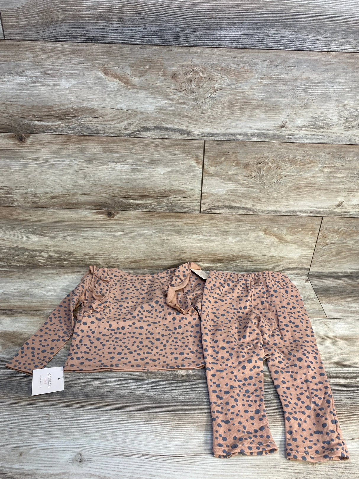 Pink long sleeve polka dot toddler shirt and pants set on wood background