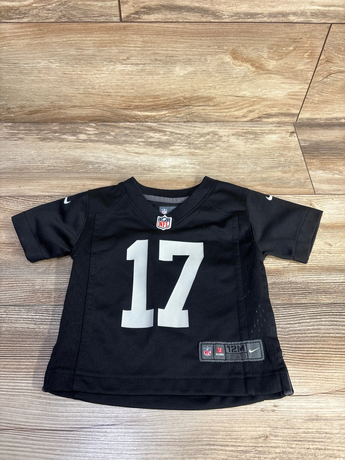 Front view of black Nike Las Vegas Raiders Davante Adams jersey, number 17, in size 12 months on a wood floor