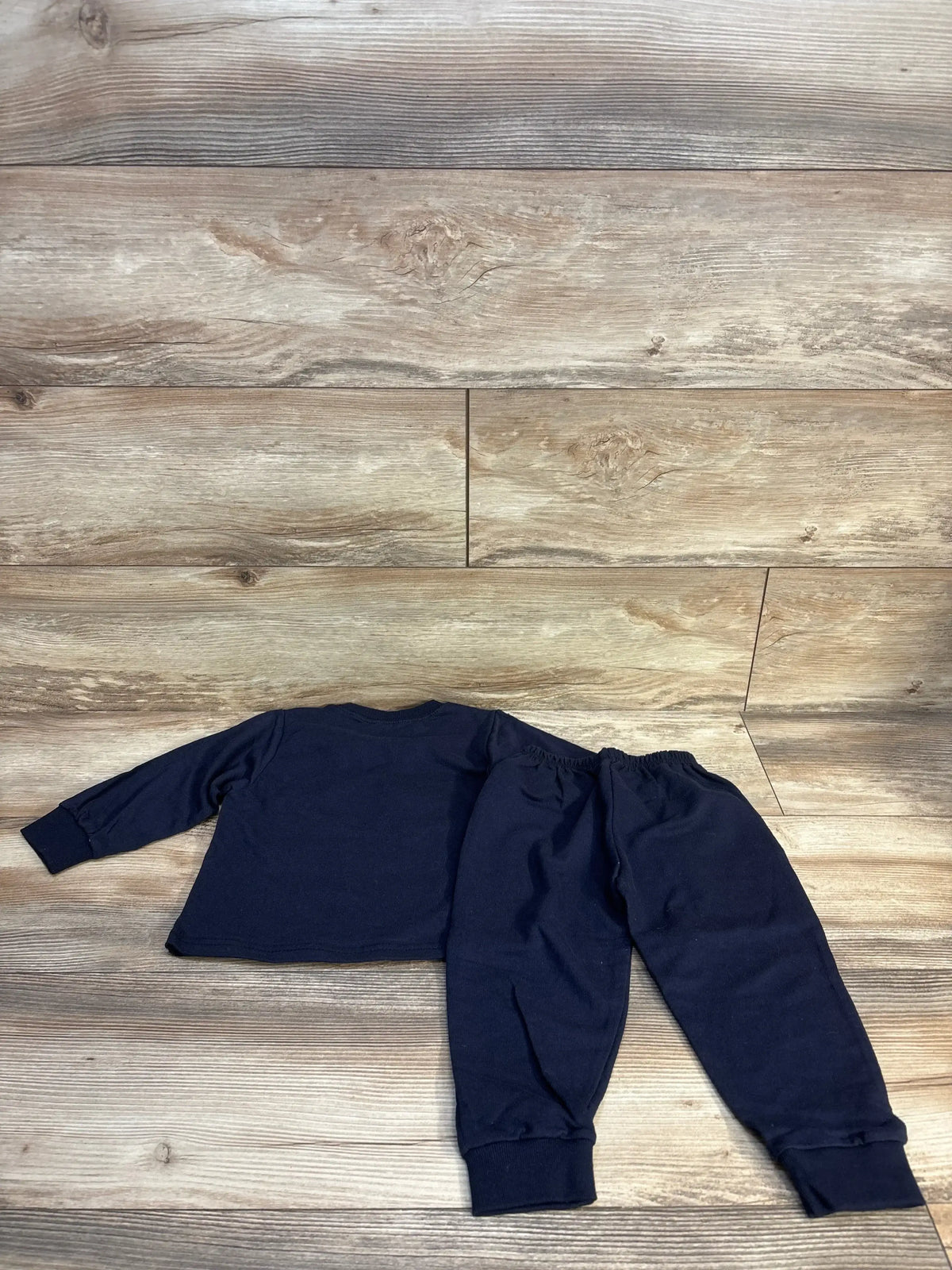 Navy blue kids long sleeve top and jogger pants set on wood floor