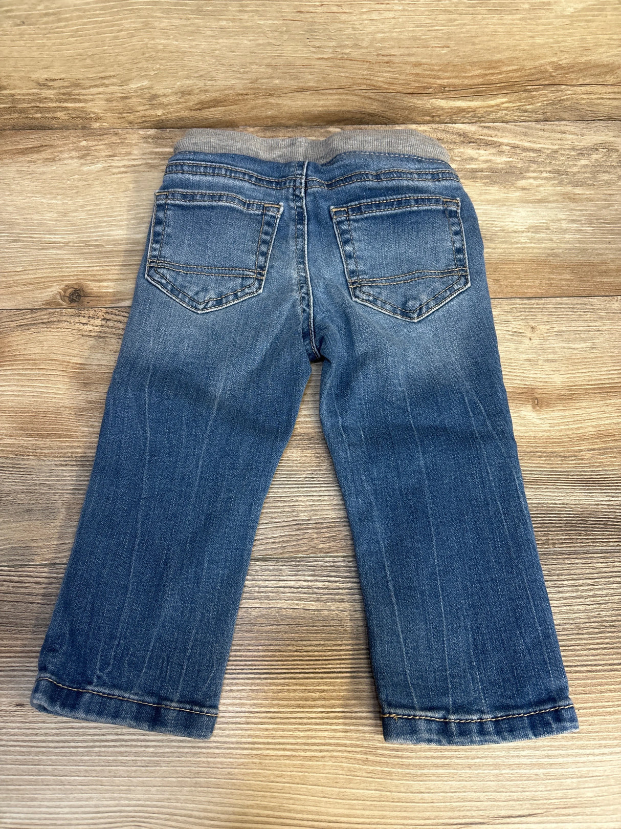 Blue denim toddler jeans with elastic waistband and back pockets on wooden background