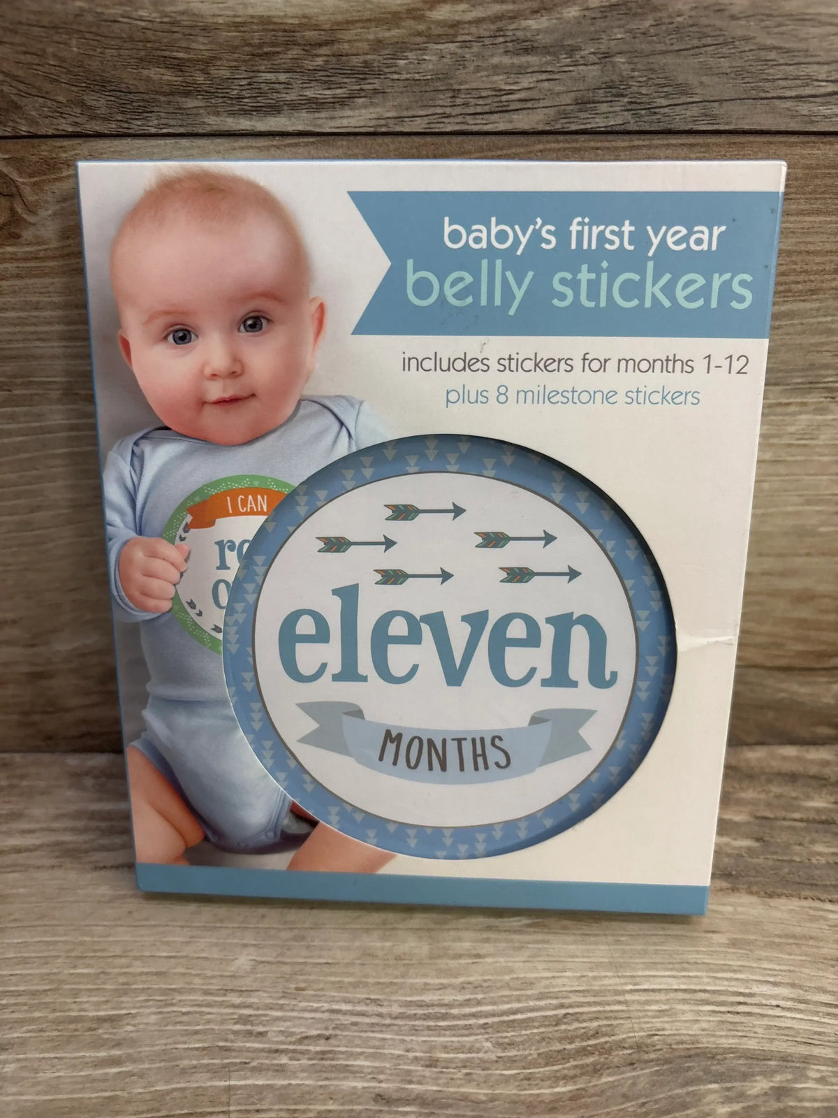 Front of Baby’s First Year belly stickers box showing product title and round eleven months milestone sticker visible through window on wood surface