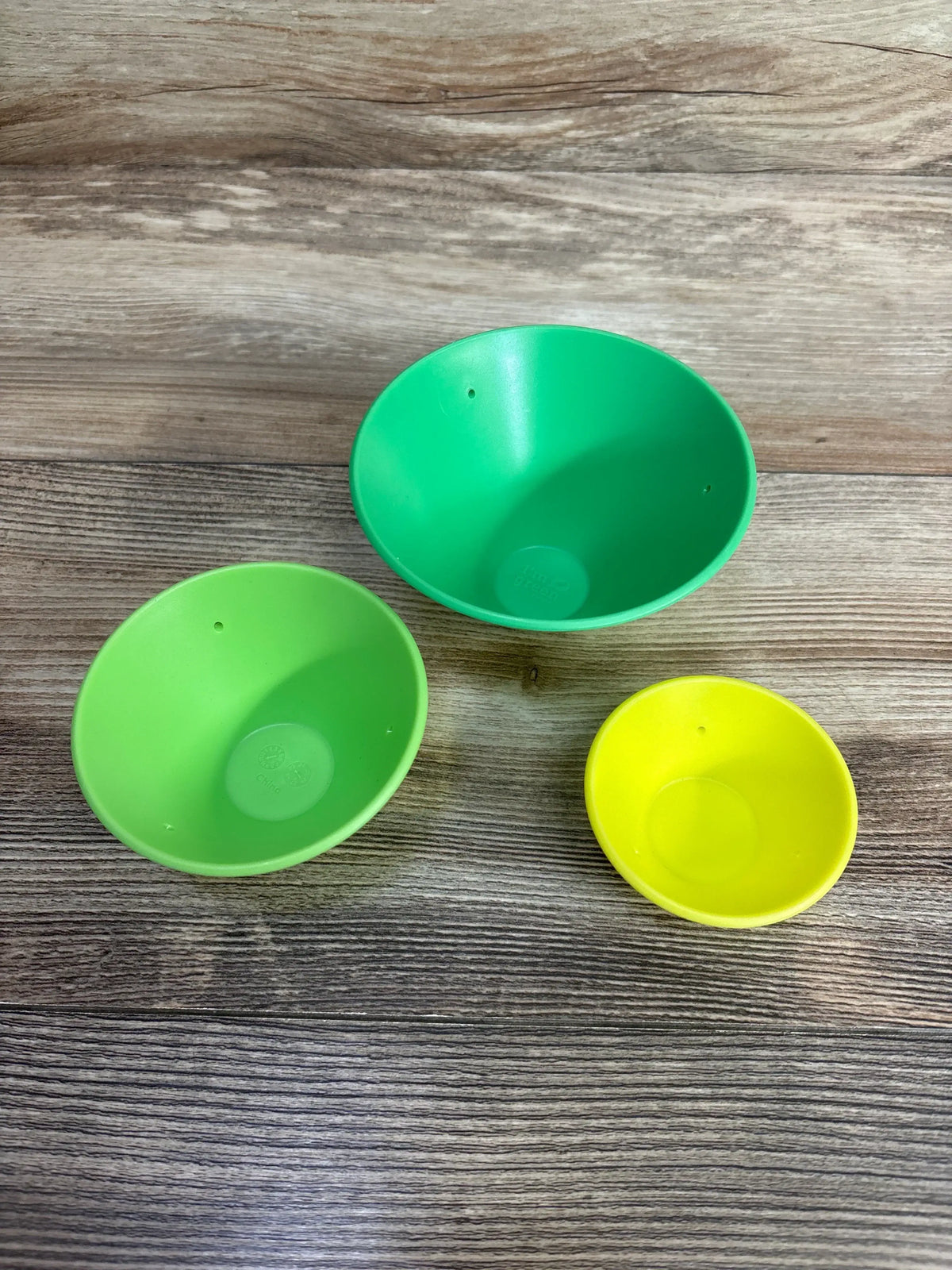 Top view of Lovevery Roll & Build Cone Set with three stackable cones: large green, medium lime, small yellow on wood background