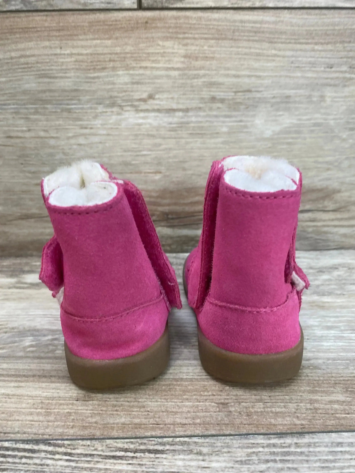 Back view of UGG Keelan Boot in pink suede with cream shearling lining and gum sole on wood plank floor