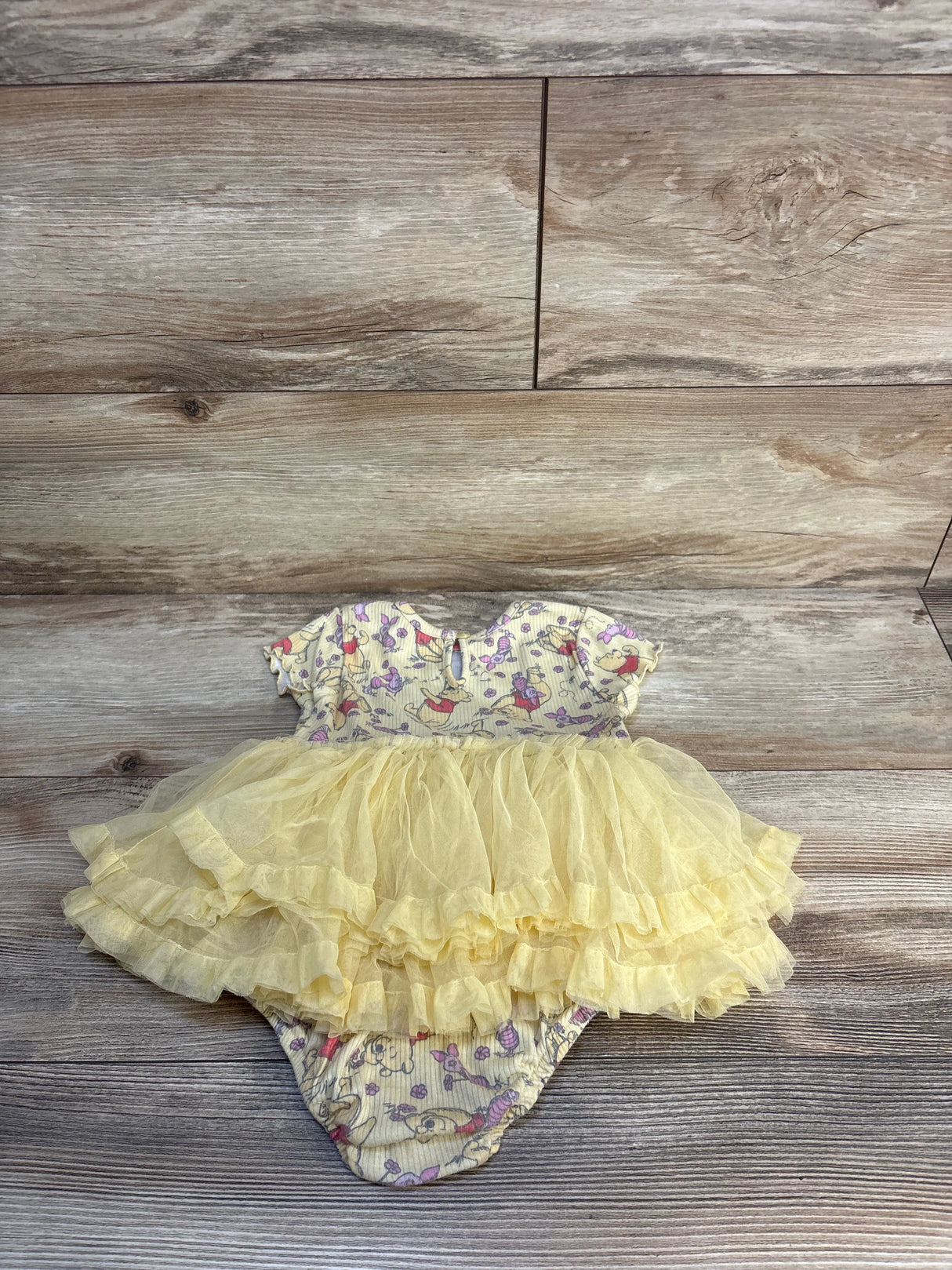 Baby girl yellow tutu dress with ruffled skirt and cute animal print bodysuit on wood floor