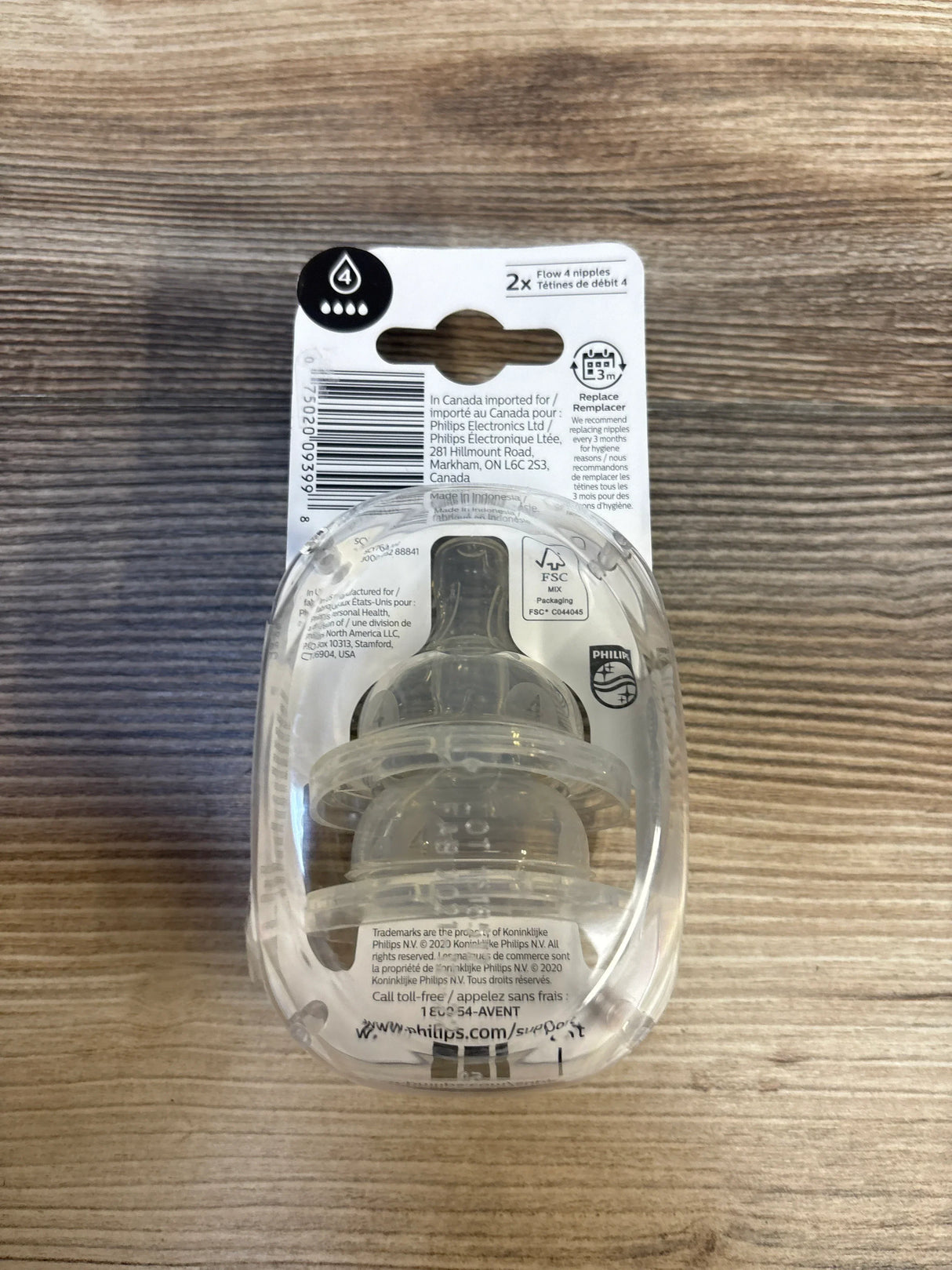 Top-down view of Philips Avent Anti-Colic Flow 4 silicone nipples 2-pack in original clear packaging on wood background