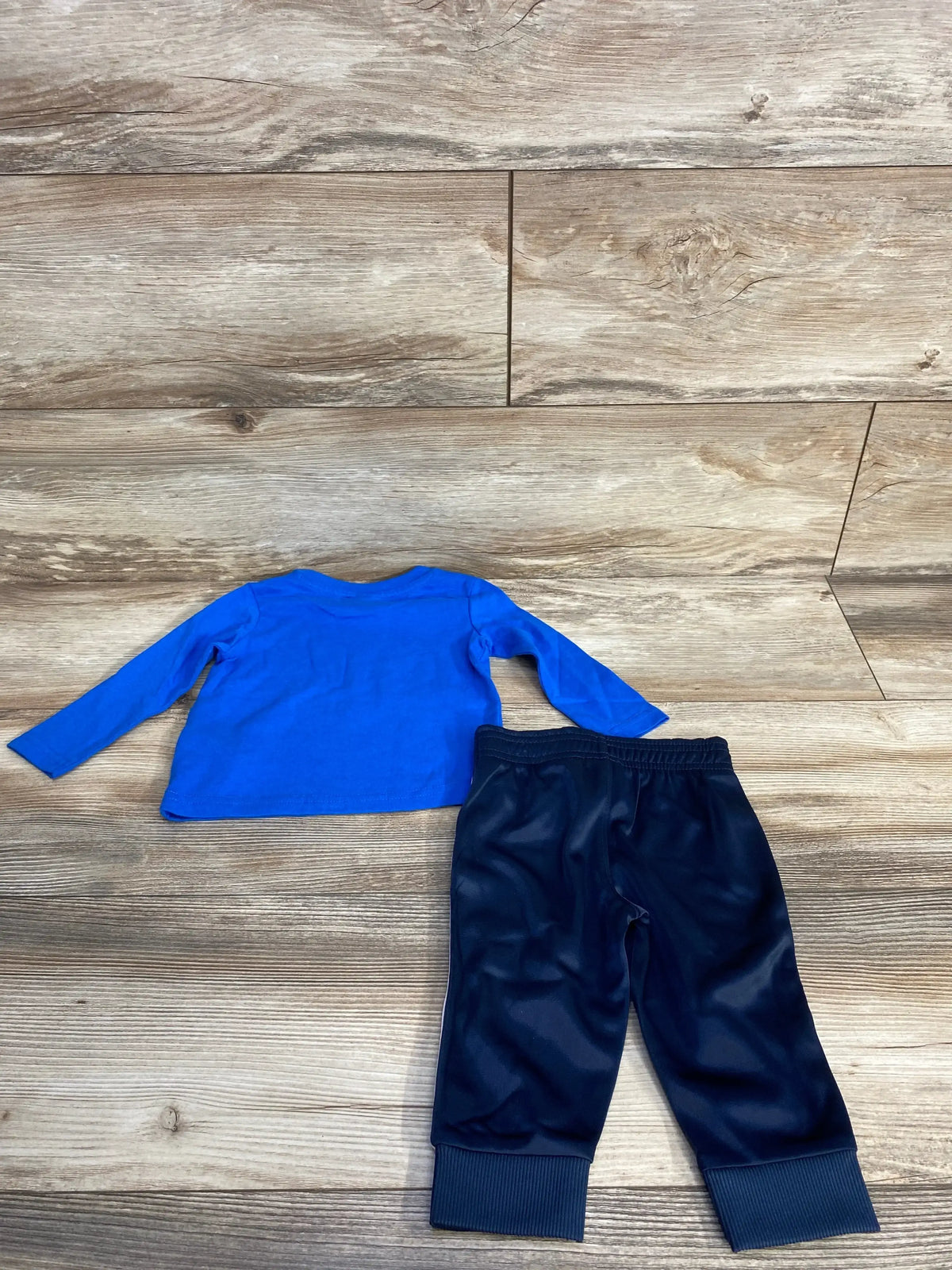 Back view of Puma blue long sleeve logo shirt and navy active jogger pants showing elastic waistband and ribbed ankle cuffs on wood floor