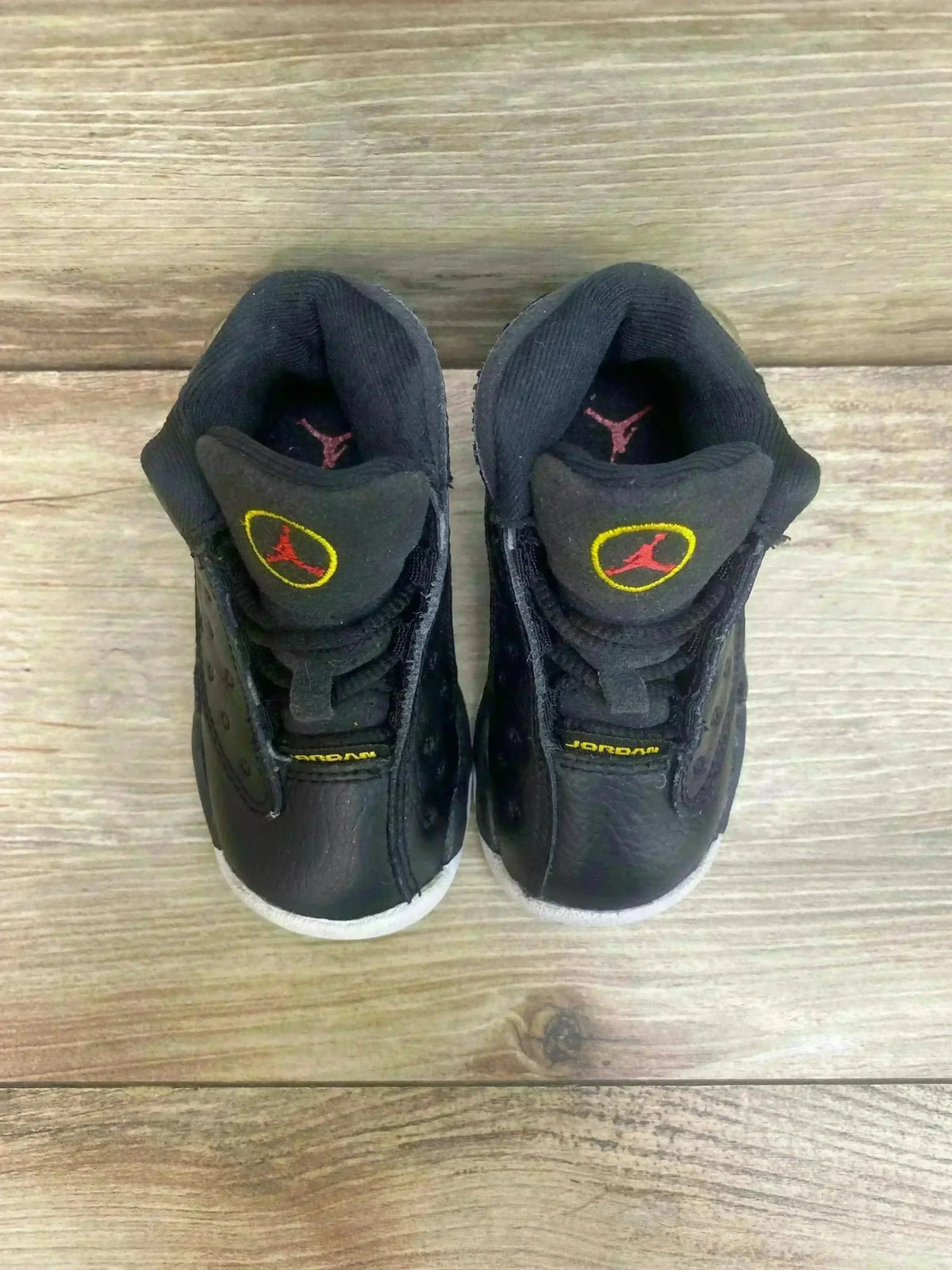 Top-down view of Air Jordan 13 'Playoff' toddler sneakers size 5C with black leather uppers and red Jumpman tongue logos
