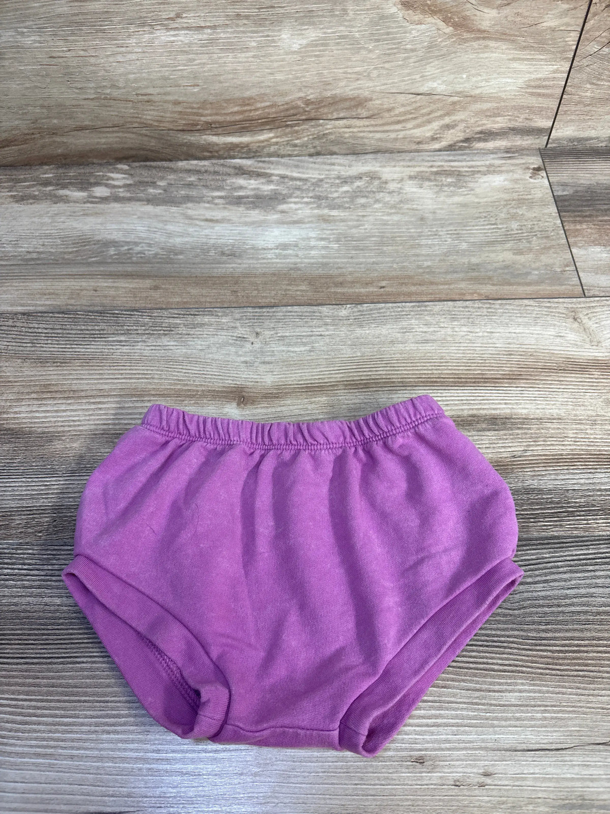Top view of pink Cat & Jack bloomers showcasing the elastic waistband and leg openings on a wood-look floor