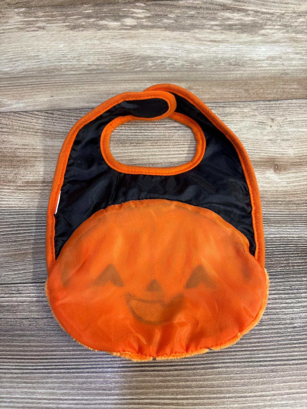 Orange pumpkin-themed baby bib with black backing, perfect for Halloween outfits and kids' costume parties.