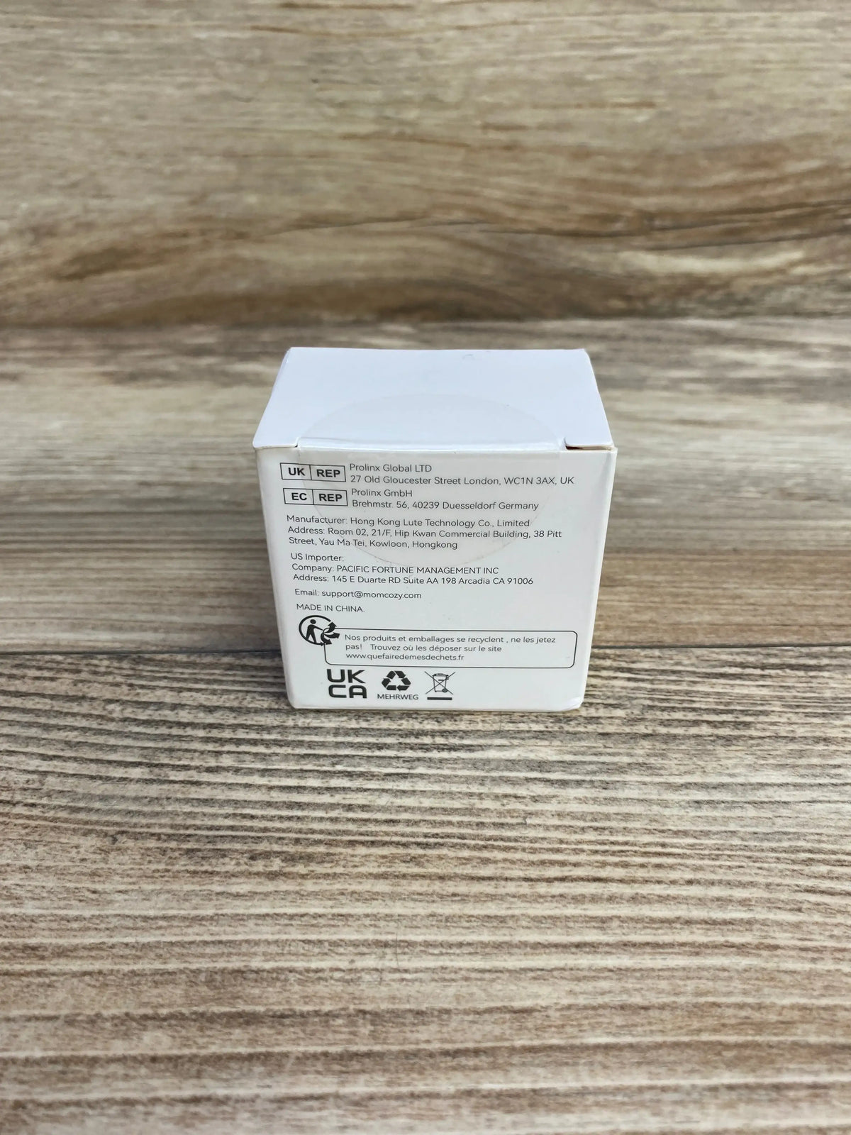 Rear of Momcozy S9/S12 Pro diaphragm and valve box with manufacturer text and certification icons on a light wood surface
