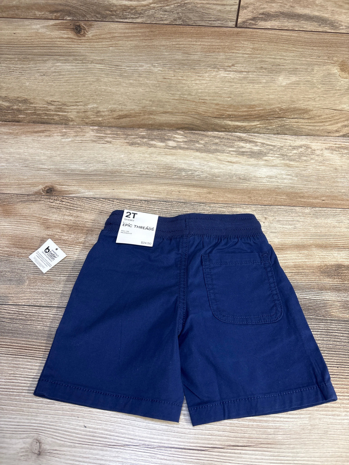 Flat lay of Epic Threads navy pull on shorts size 2T showing elastic waistband and back patch pocket on wood floor