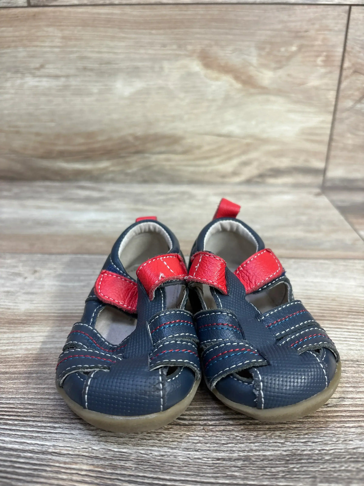 Front view of navy See Kai Run Fisherman toddler sandals size 3C showcasing red Velcro straps and textured toe on wood background