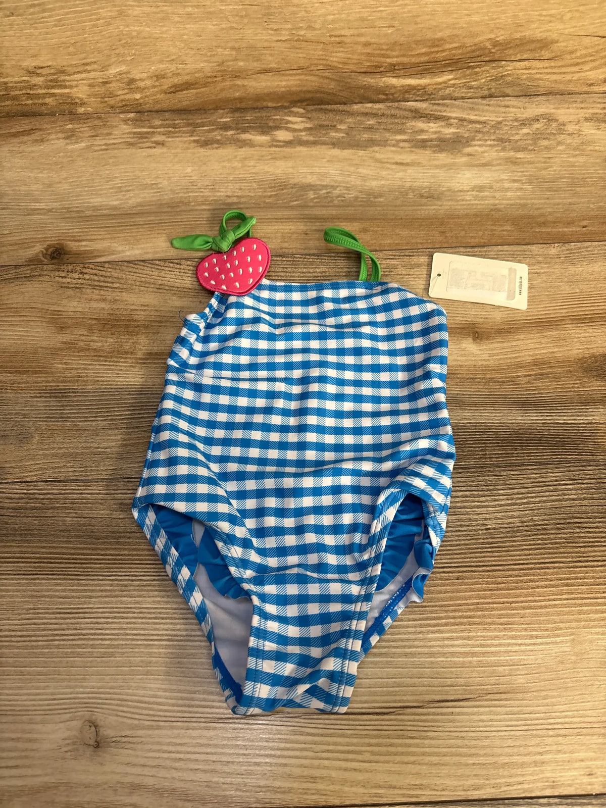 Front view of Adventurewear 360 blue one-piece swimsuit, size 18 months, with gingham pattern and green straps on wood background