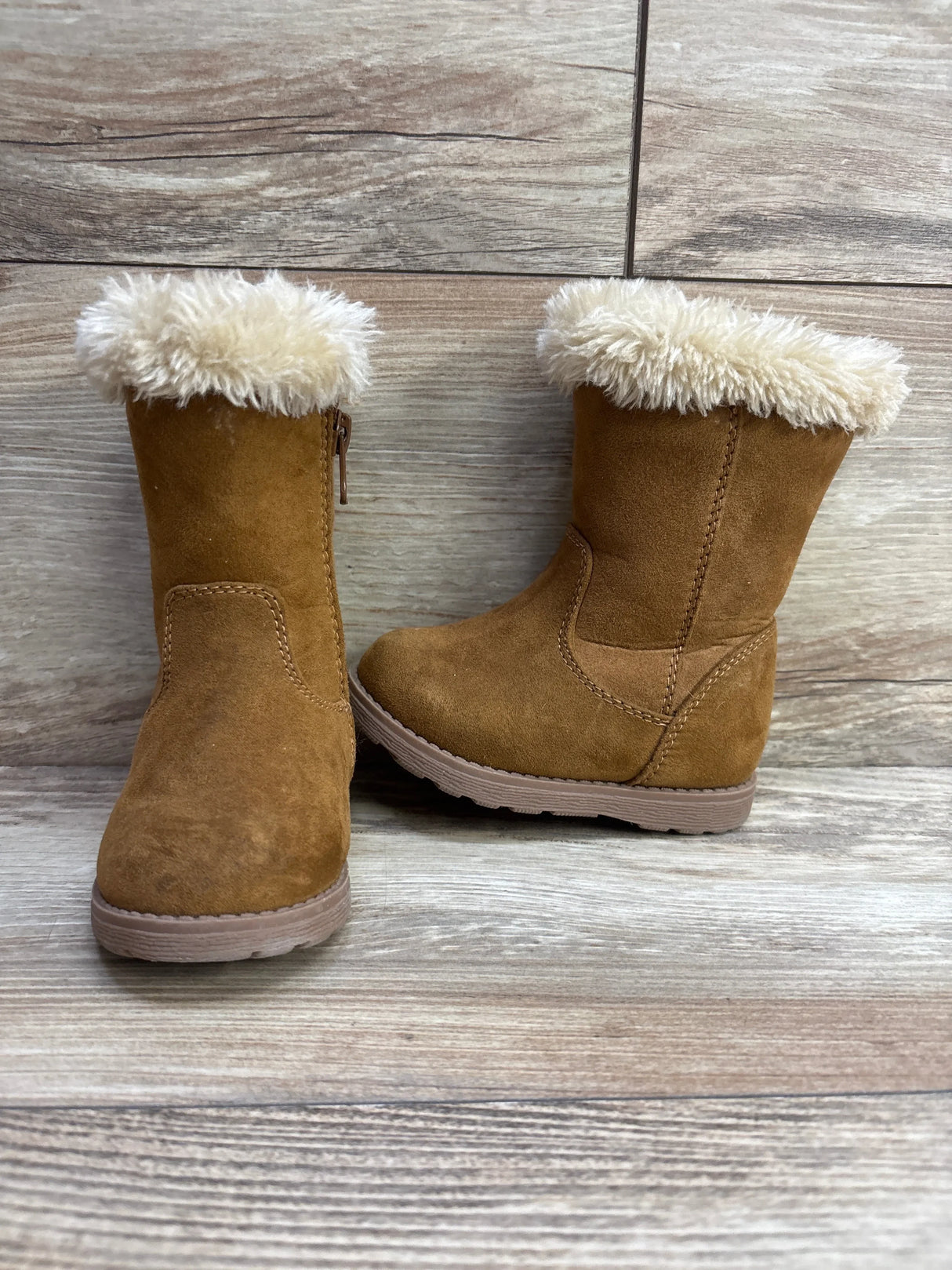 Children's brown faux suede winter boots with cream faux fur lining on wooden floor