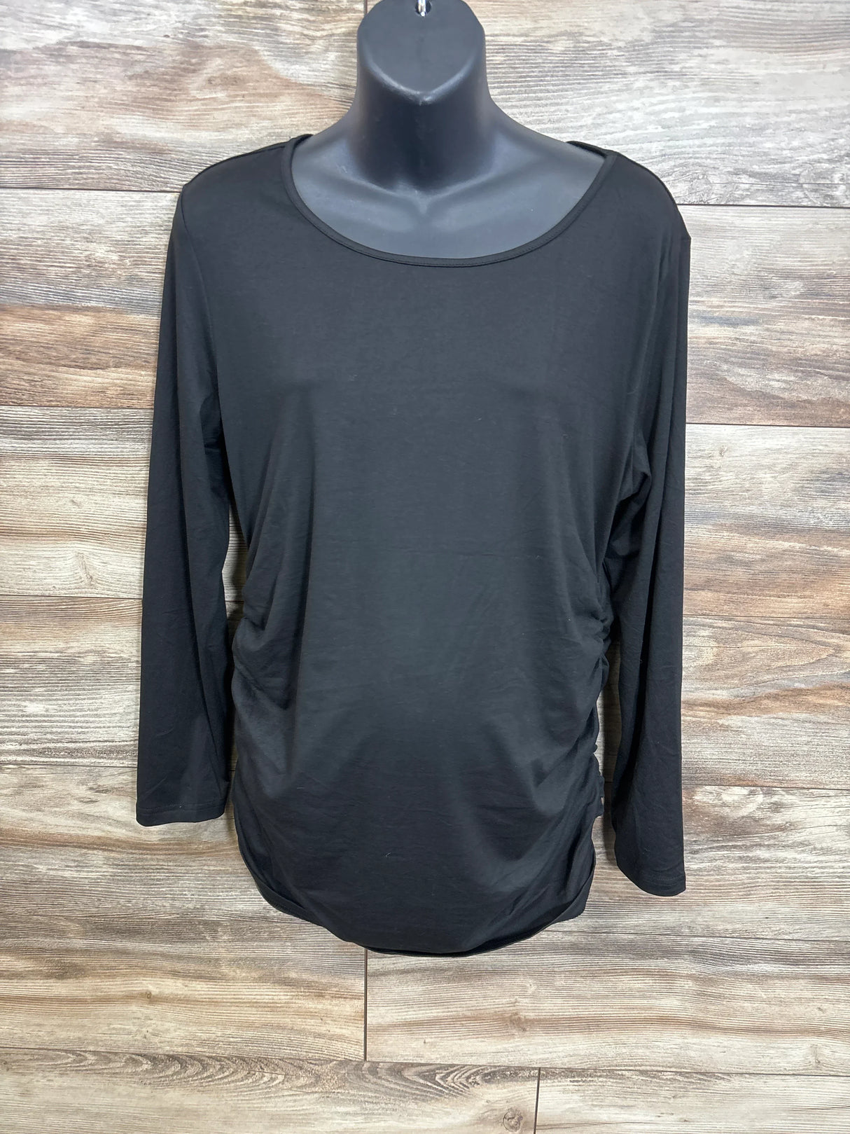 Black maternity long sleeve shirt with ruched sides on mannequin, wood background
