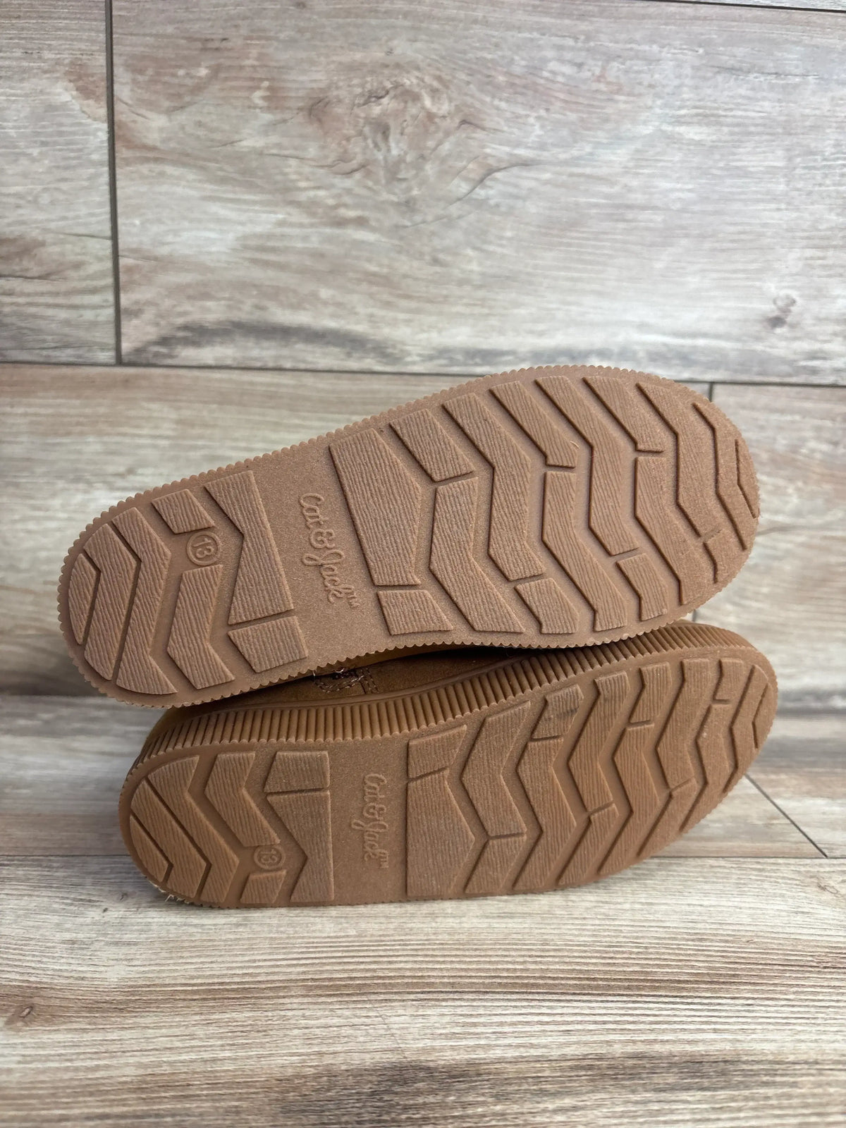 Bottom view of Cat & Jack Natalia tall shearling-style toddler boots showing textured rubber soles and size 13 on wood floor