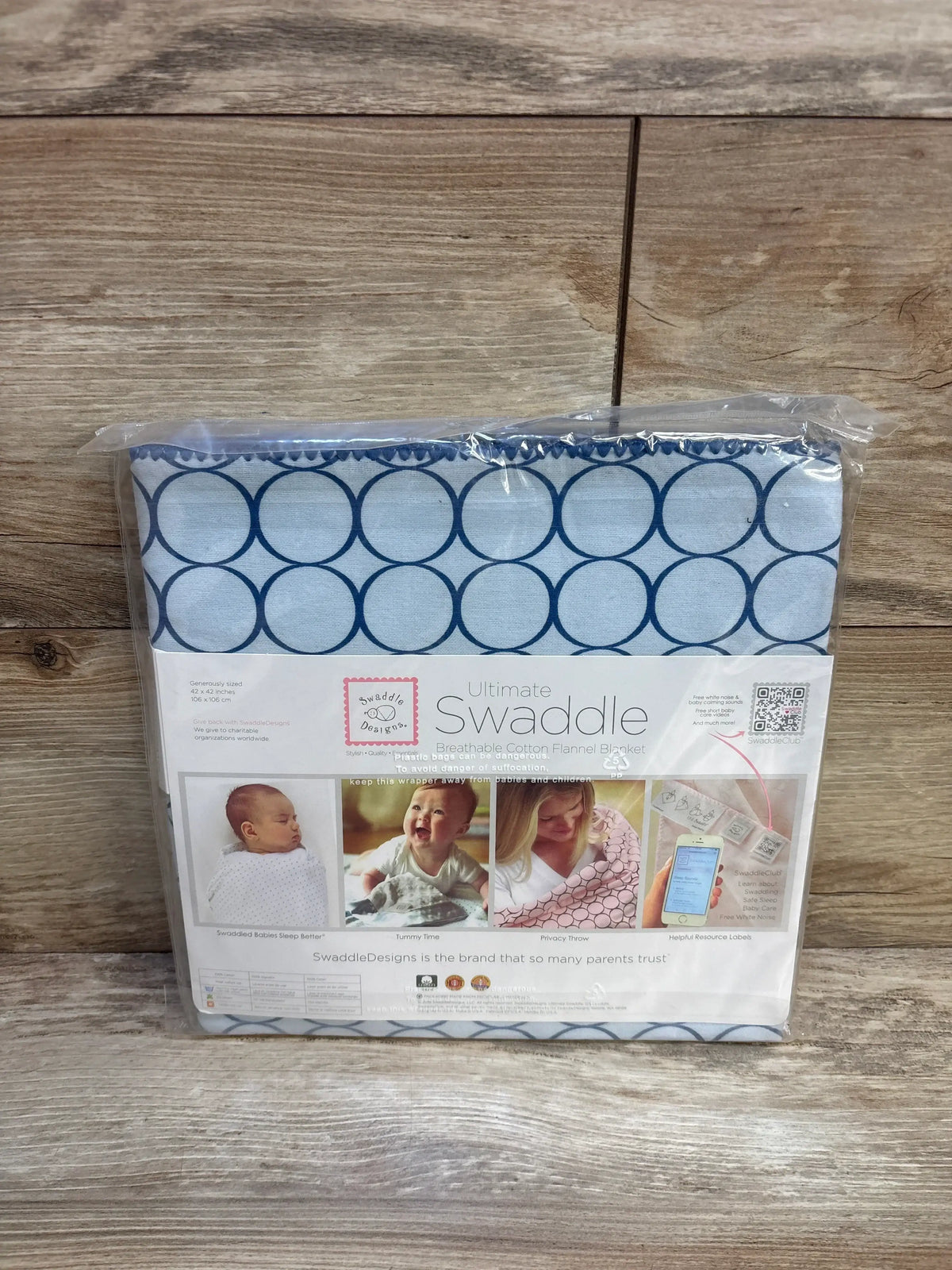 Blue circle pattern cotton swaddle blanket in package on wood background, for babies.