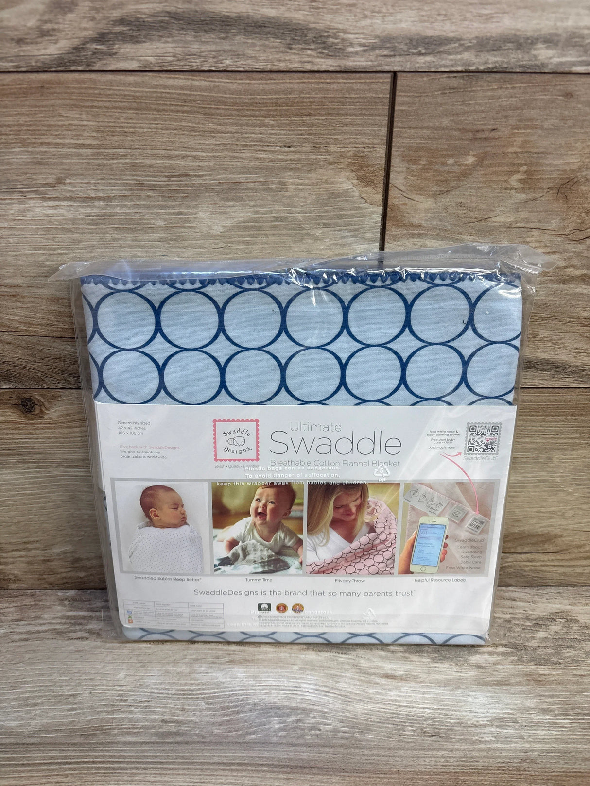 Blue circle pattern cotton swaddle blanket in package on wood background, for babies.
