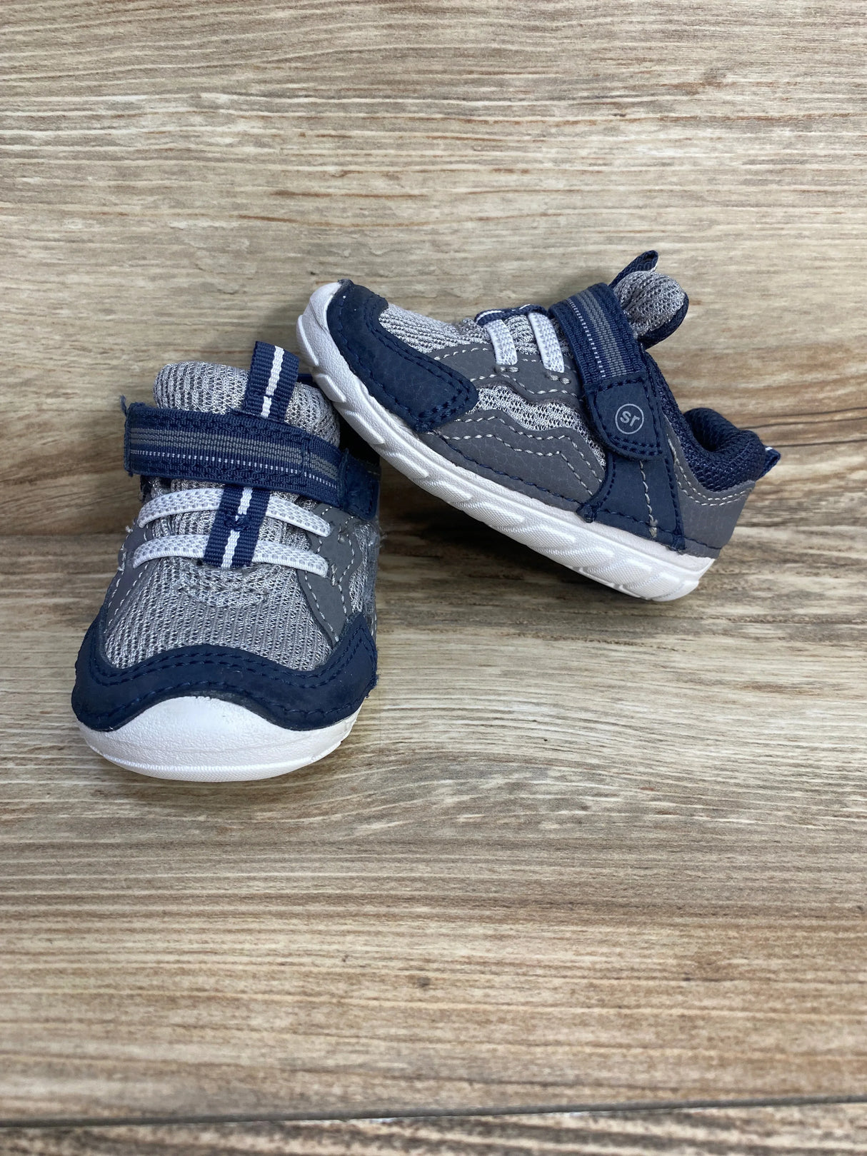 Front and side view of Stride Rite Kylo toddler sneakers in navy and gray showing mesh upper, Velcro strap, and white sole on wood background