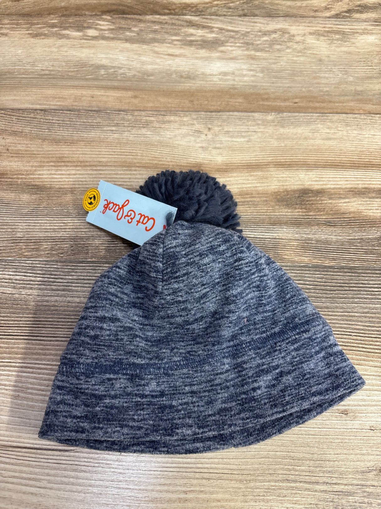 gray knit winter hat with pom pom on wooden surface, tag reading Cat & Jack