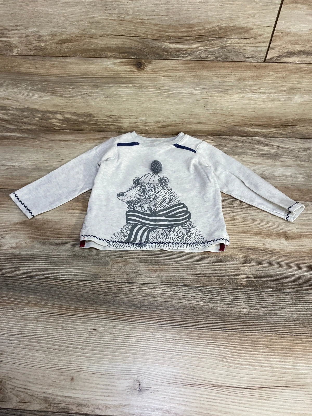 Flat lay of grey Mud Pie long-sleeve shirt (12-18 months) showing bear graphic with pom pom hat and striped scarf on wood