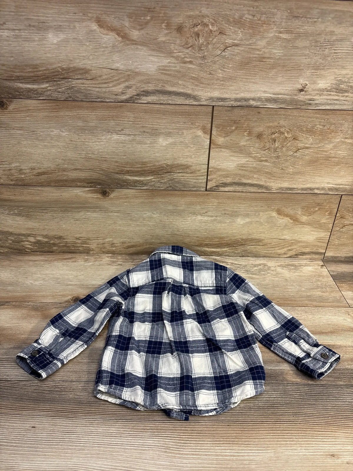 Back view of toddler navy and white plaid flannel shirt, size 2T, showing button cuffs and gathered back on wood background