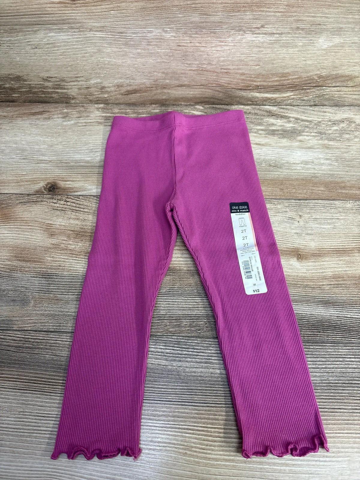 Toddler size 2T pink ribbed leggings with lettuce hem on wooden background