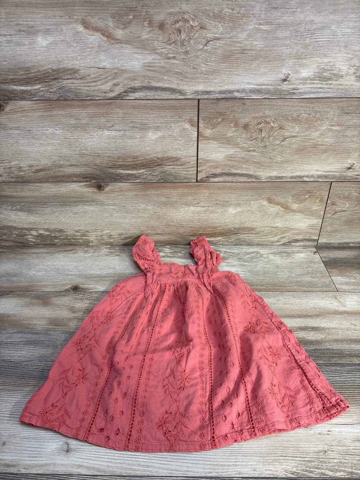 Flat lay of Baby Gap girls' red eyelet dress showcasing flutter sleeves and embroidered eyelet panels on light wood background