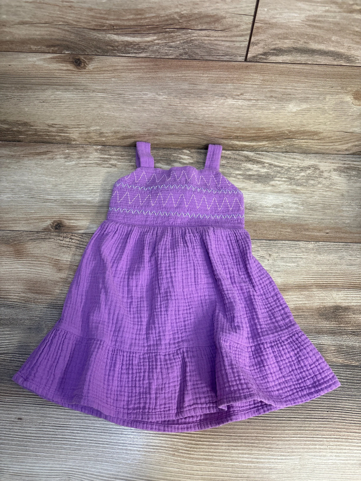 Purple toddler sundress with smocked bodice and ruffle hem on wooden background