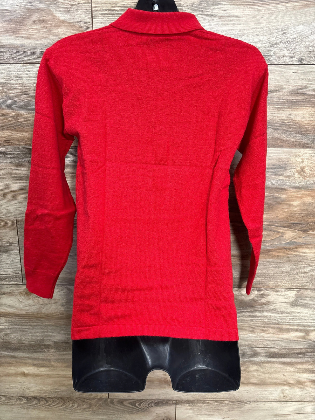 Red long sleeve knit shirt for kids on mannequin with wood background
