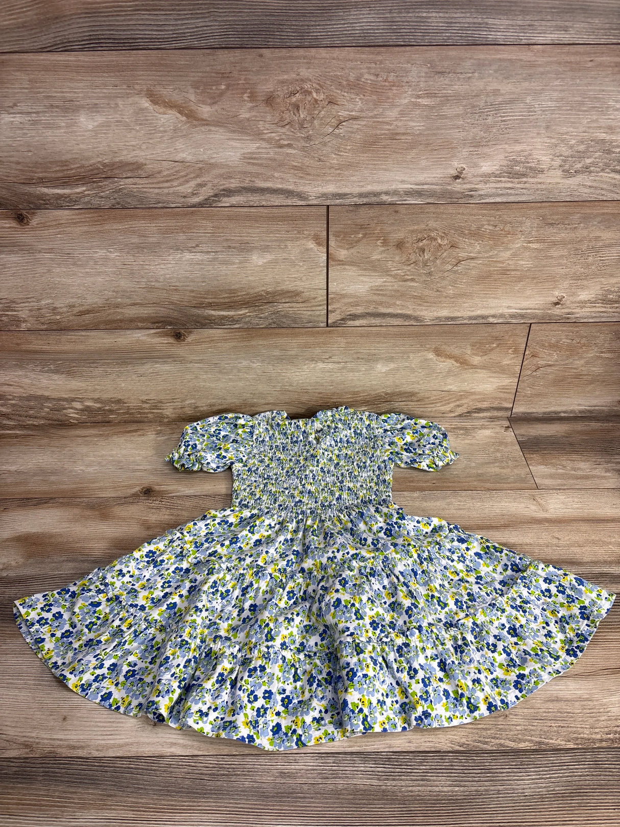 Floral short-sleeve girls dress with blue and yellow flowers on wood background