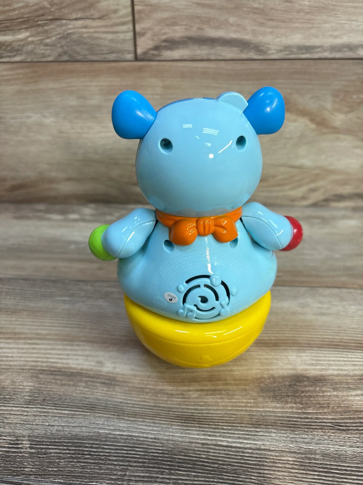 Front view of VTech Count & Cobble Cody showcasing its light blue body, orange bow tie, and yellow wobbling base on a wood surface