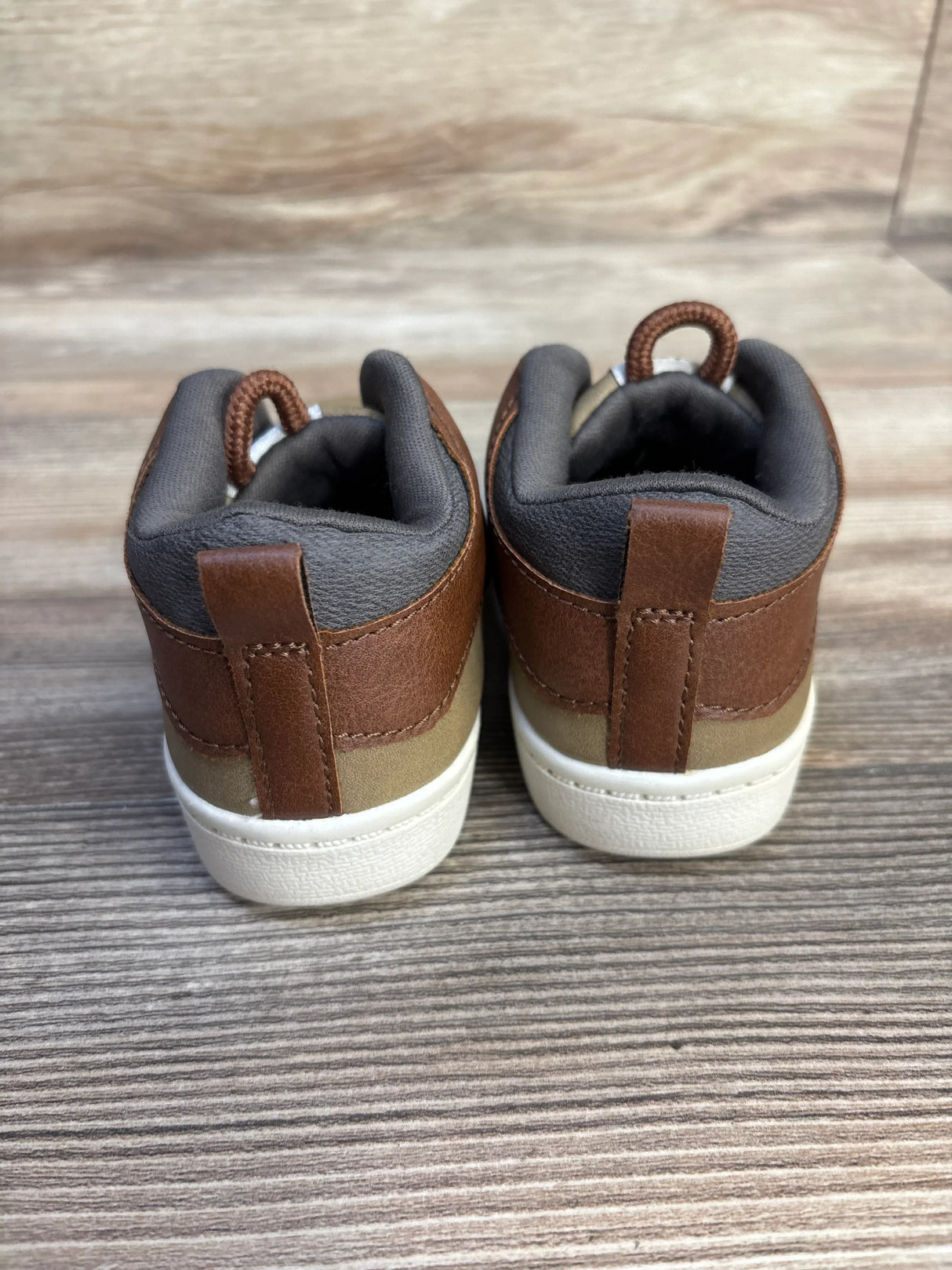 Back view of brown and tan toddler sneakers with white soles on wood background