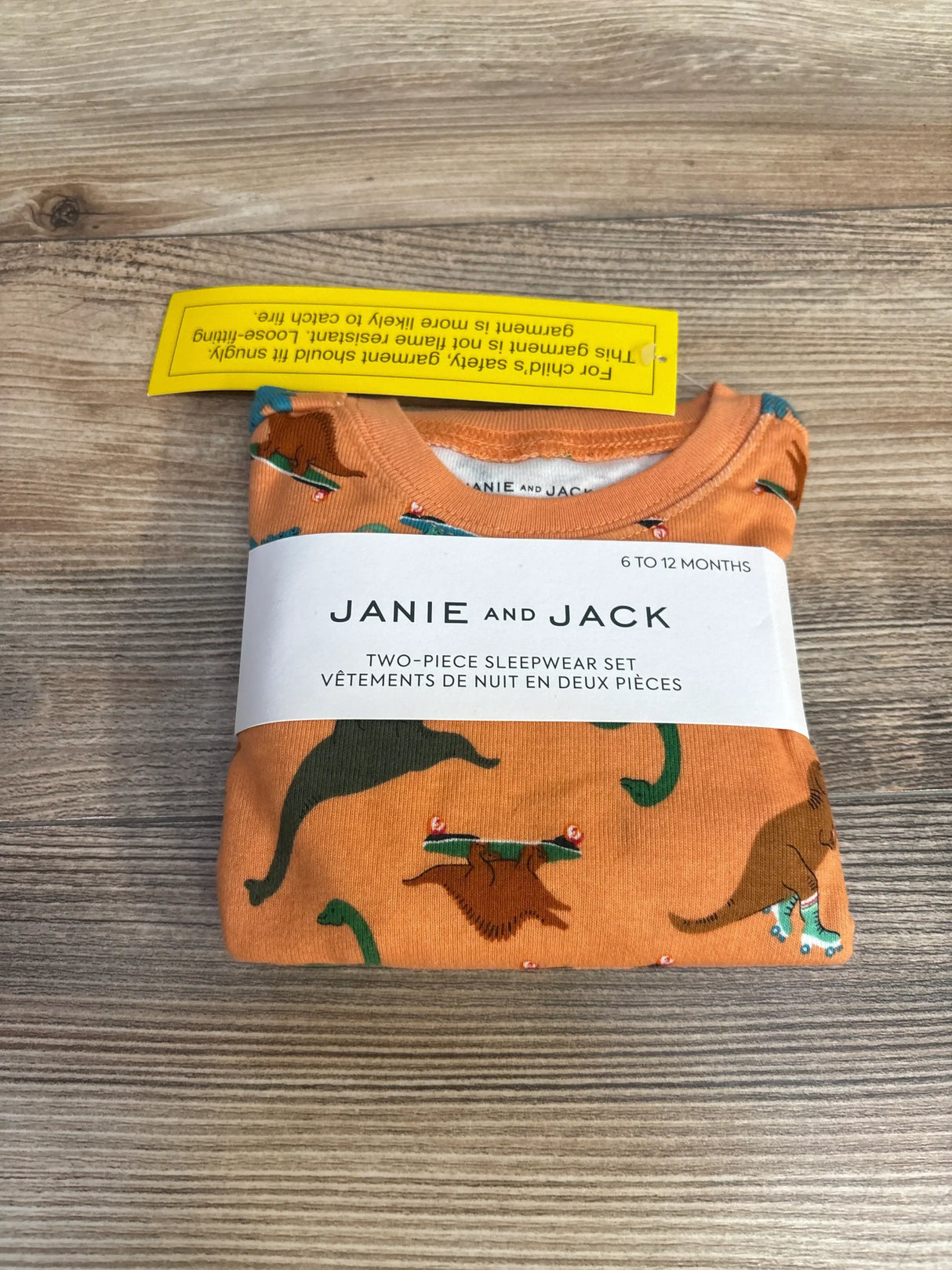 Janie and Jack two-piece orange dinosaur print sleepwear set for 6 to 12 months on wooden surface