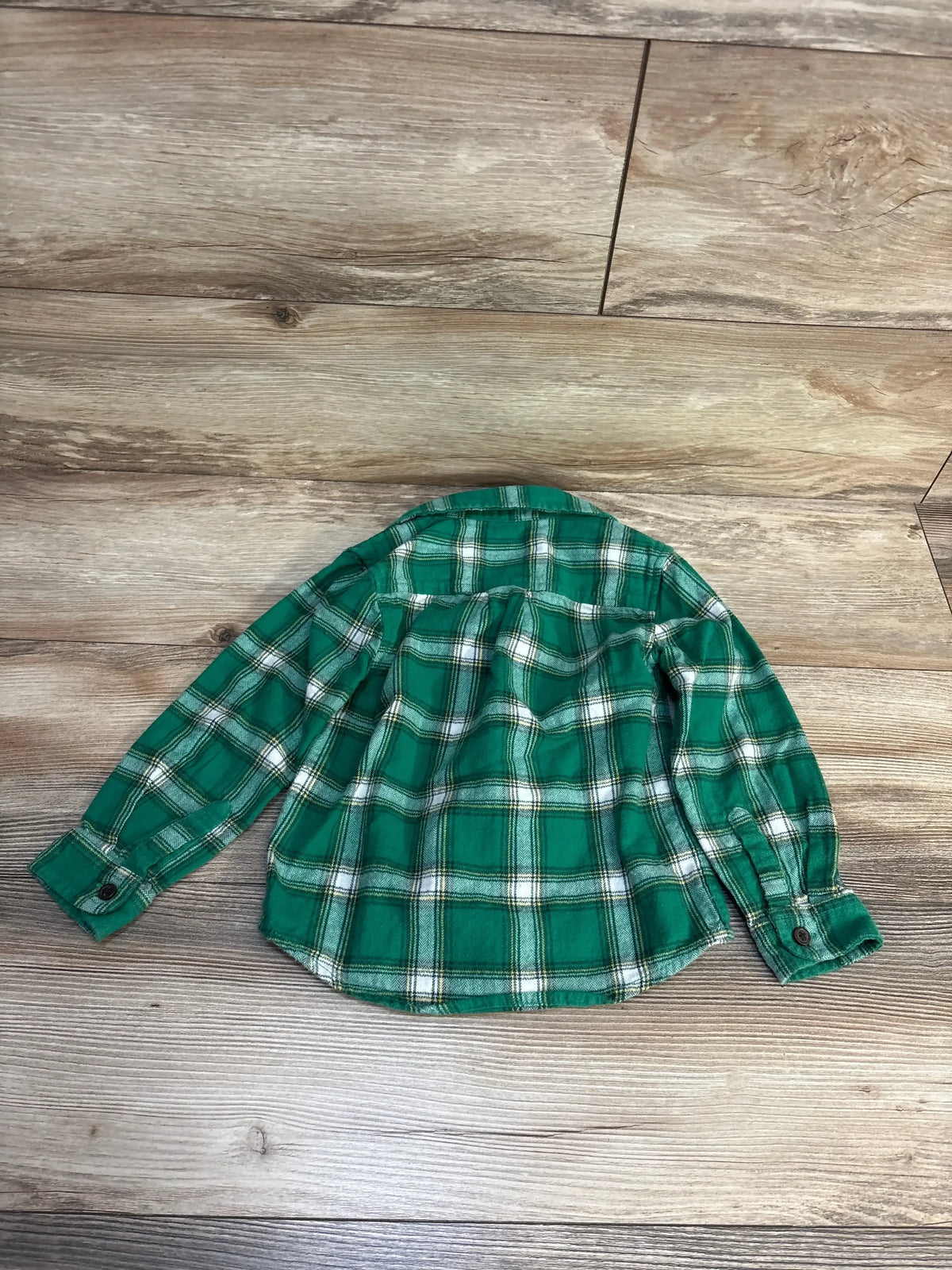 Back view of green Cat and Jack toddler plaid flannel button-up shirt showing long sleeves, button cuffs, and curved hem on wood floor