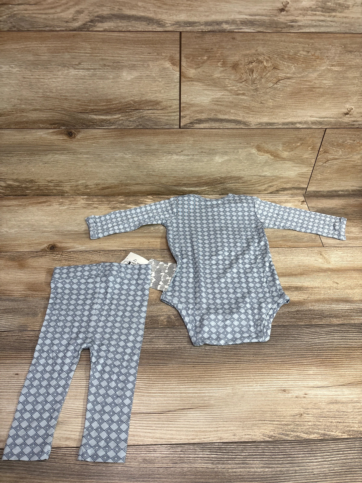 Kate Quinn blue bamboo long sleeve bodysuit and pants set for infants on a wood background