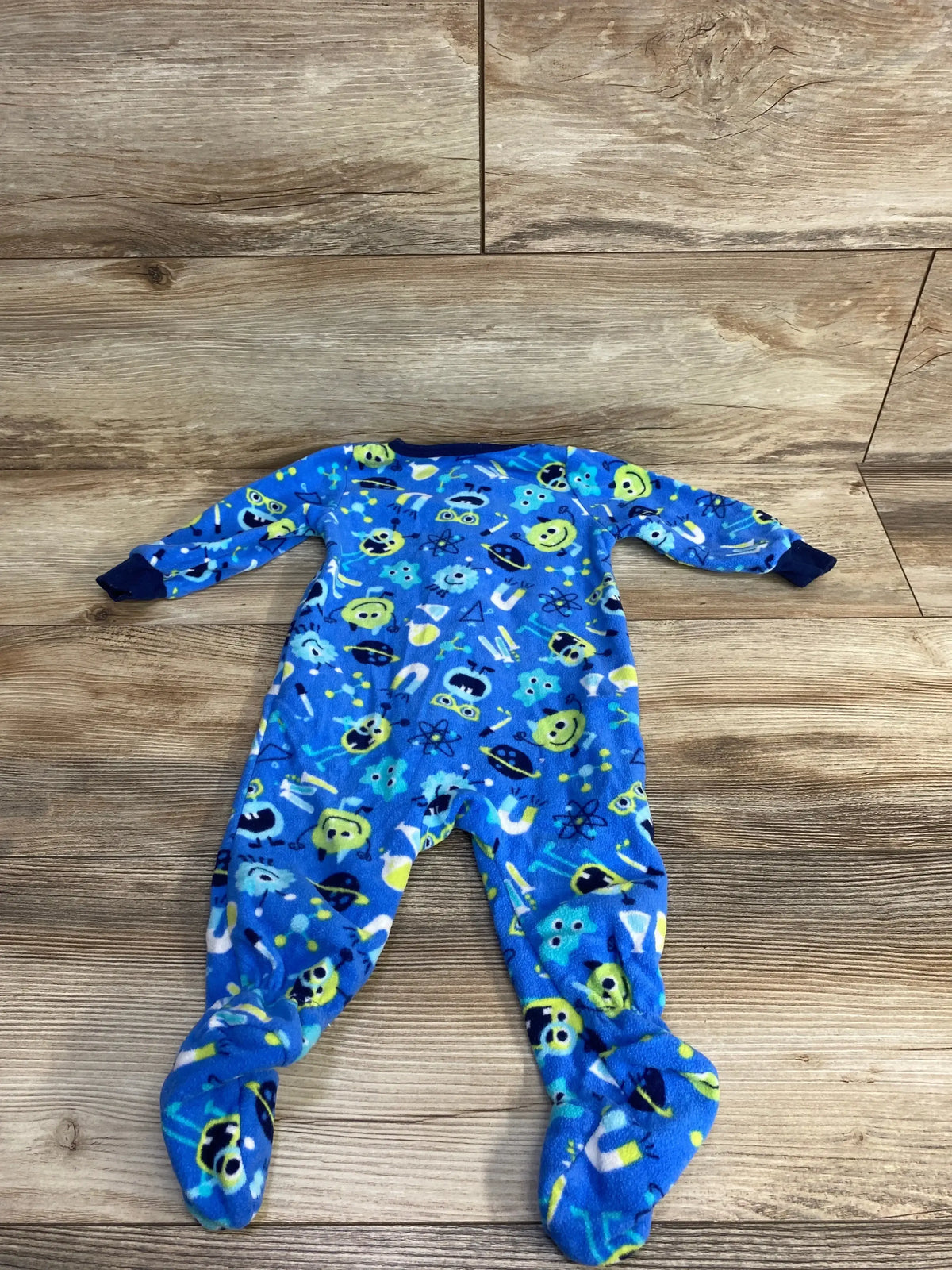 Blue fleece infant footed pajamas with colorful science-themed prints on wooden floor