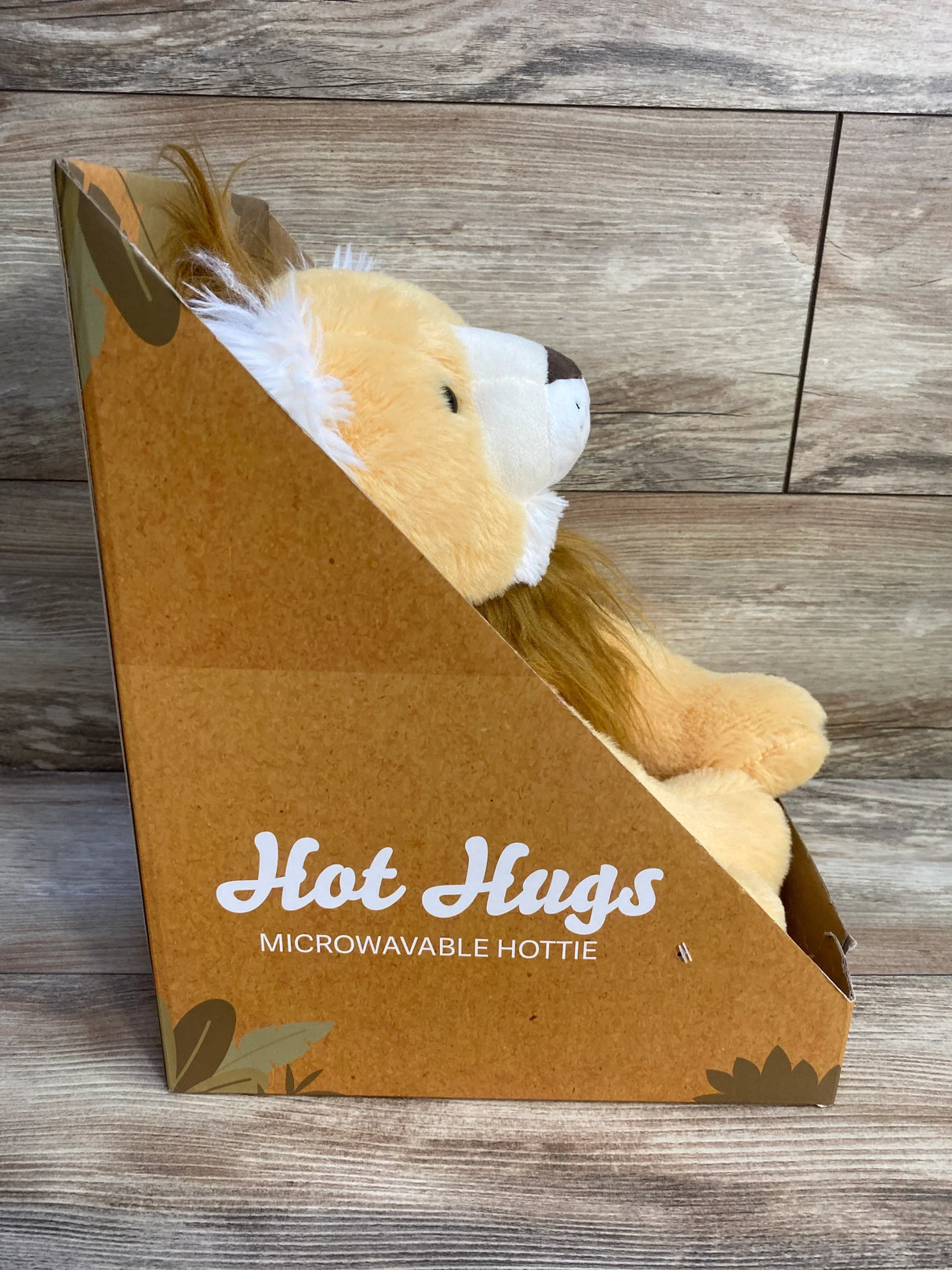 Plush lion microwavable hottie in brown Hot Hugs box on wood background