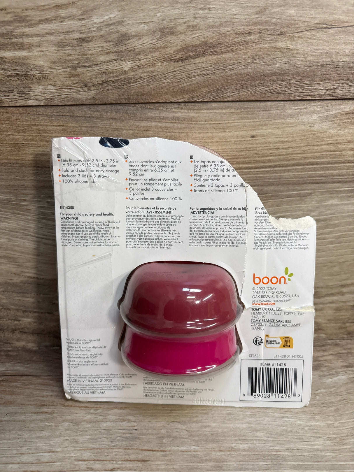 Back packaging of Boon snug silicone lids for cups in red and pink colors on wooden surface