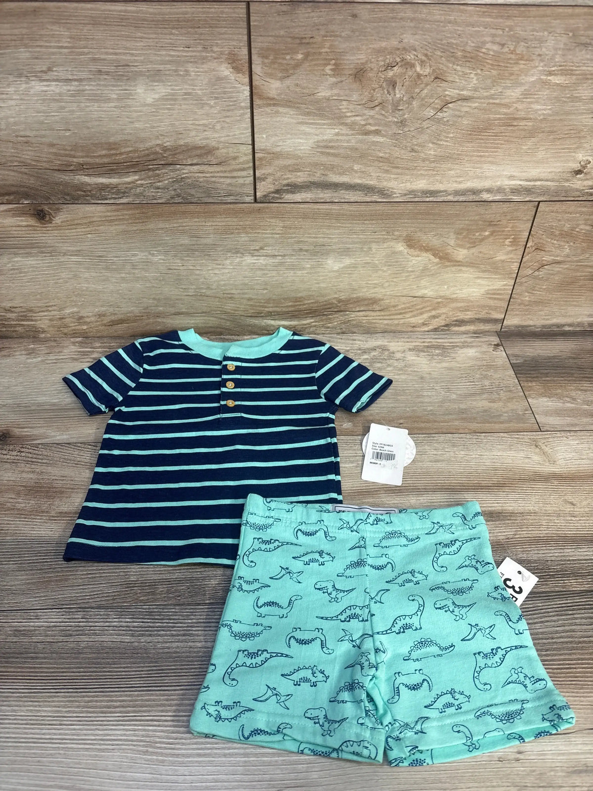 Navy striped toddler shirt with mint dinosaur print shorts on wood background