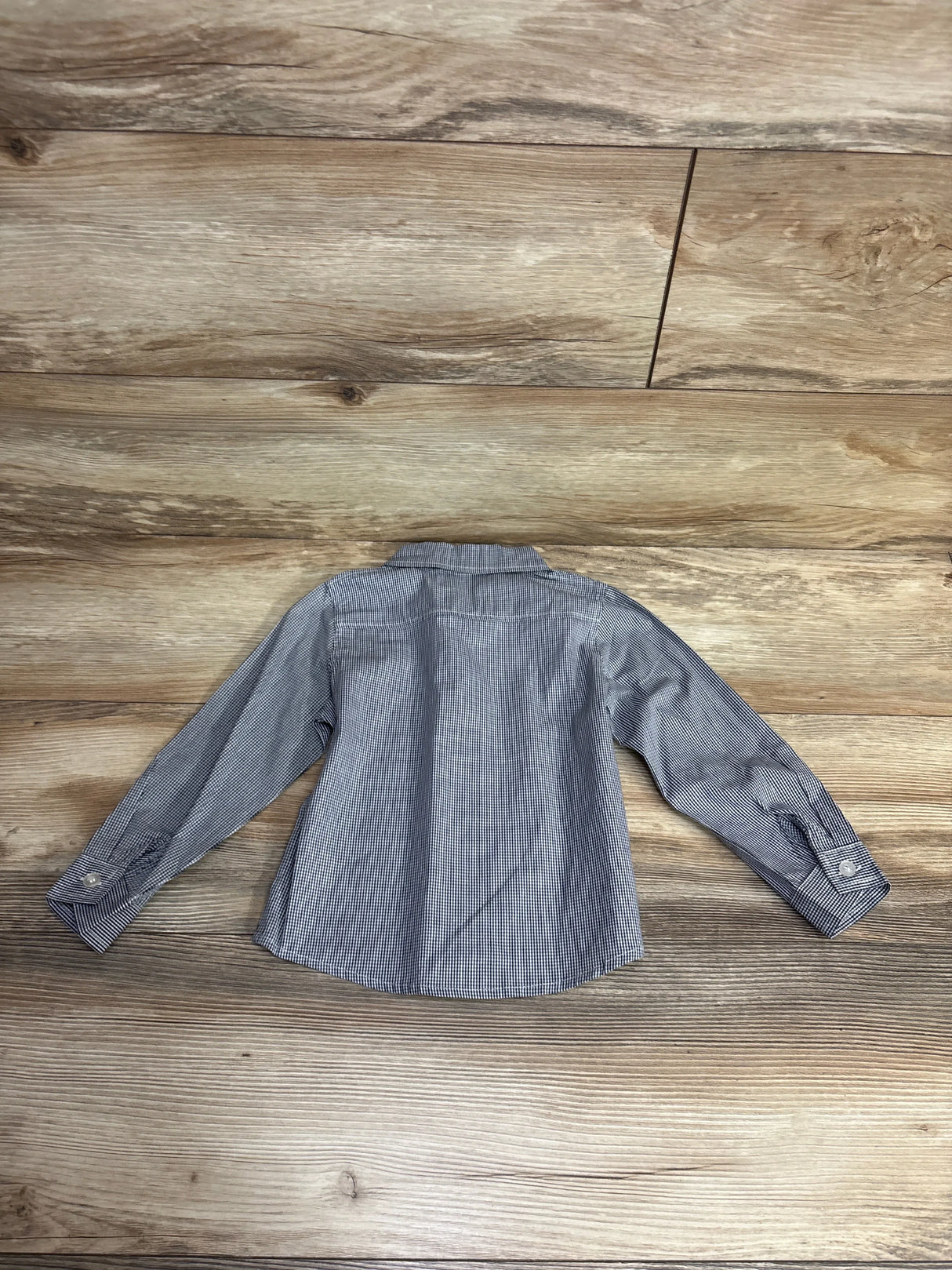 Long sleeve children's checkered button-up shirt displayed on wooden floor