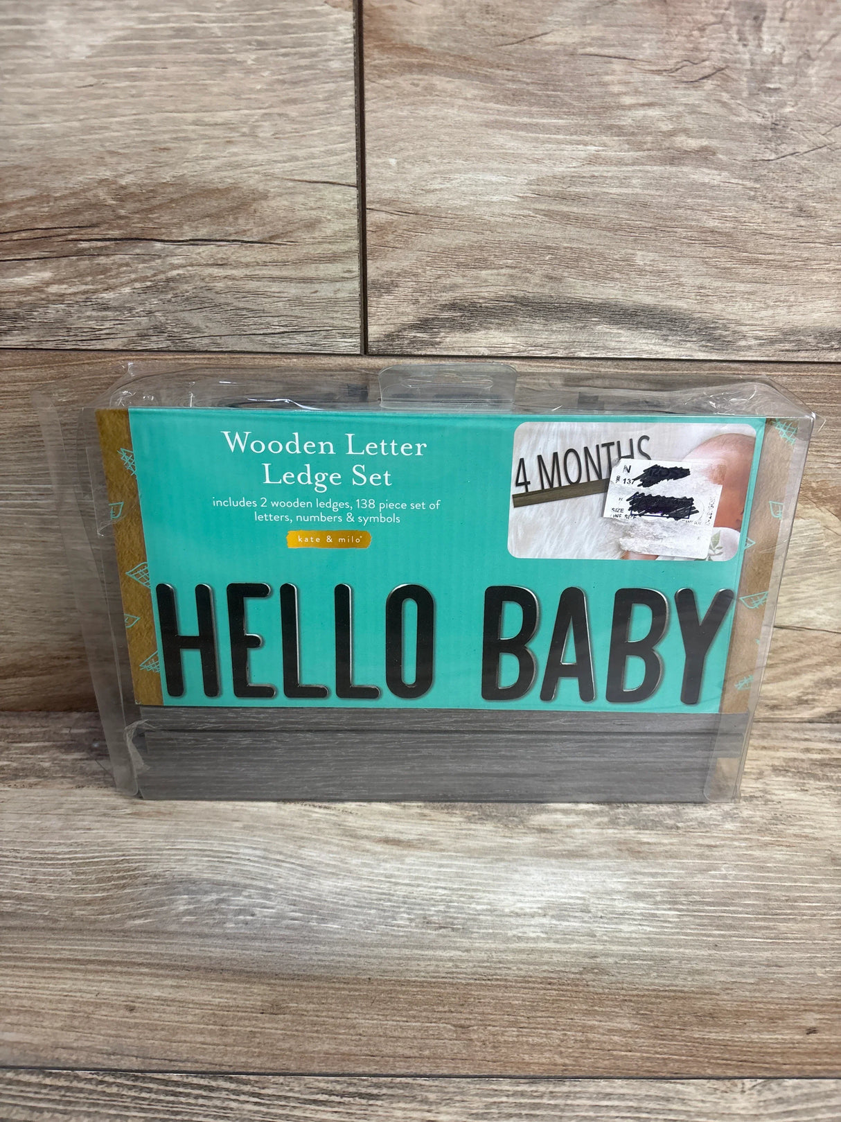 Wooden Letter Ledge Set packaging with black letters spelling HELLO BABY on teal background