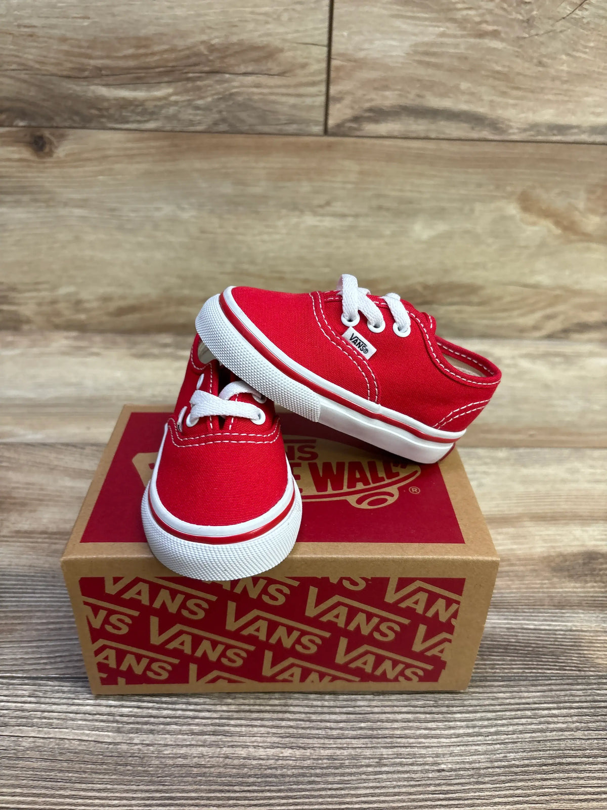 Front and side views of red Vans Authentic lace-up sneakers showcasing white laces and soles on a Vans shoebox