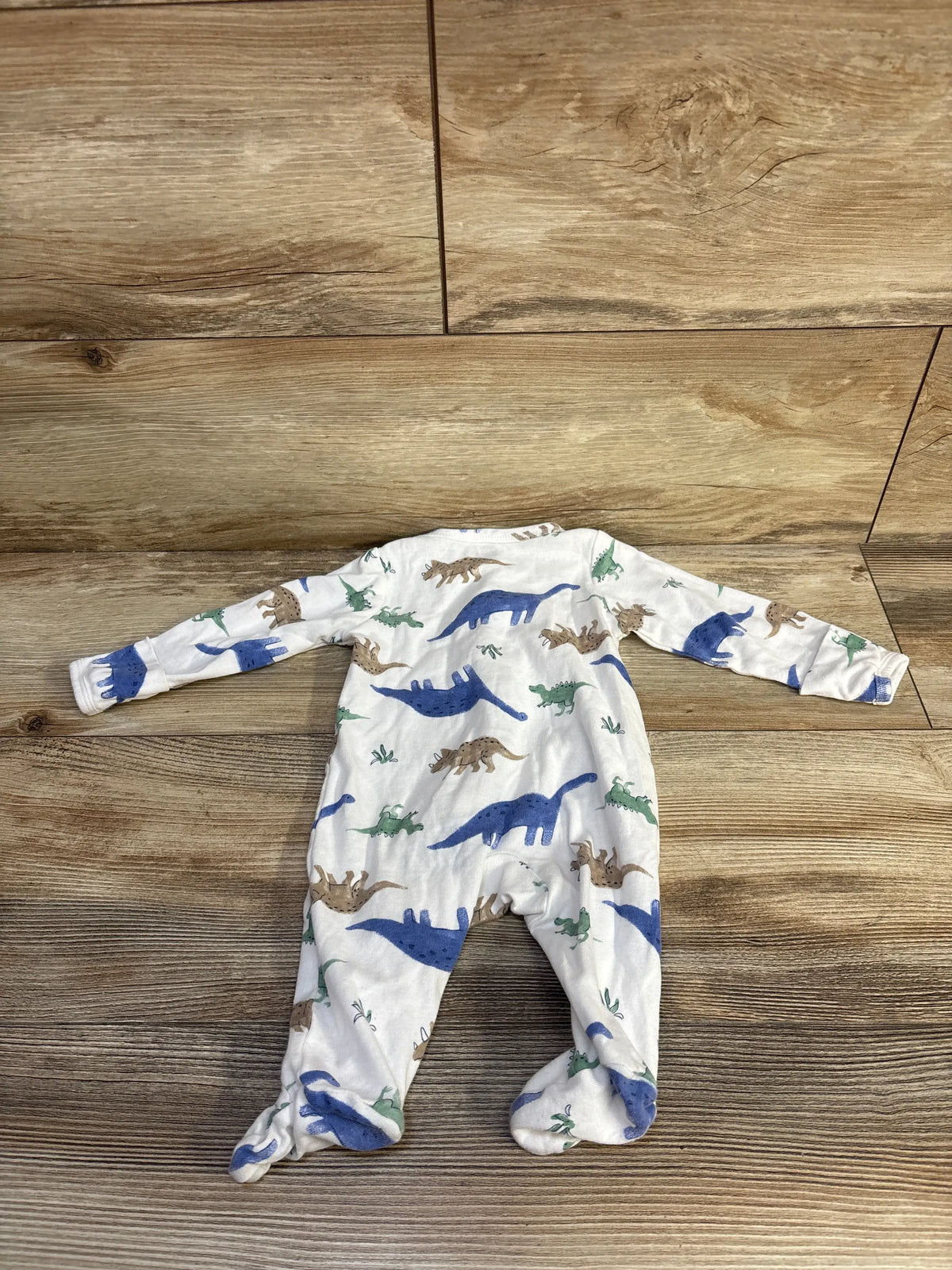 Flat lay of Just One You dinosaur sleeper in white cotton with footed legs and colorful dinosaur print