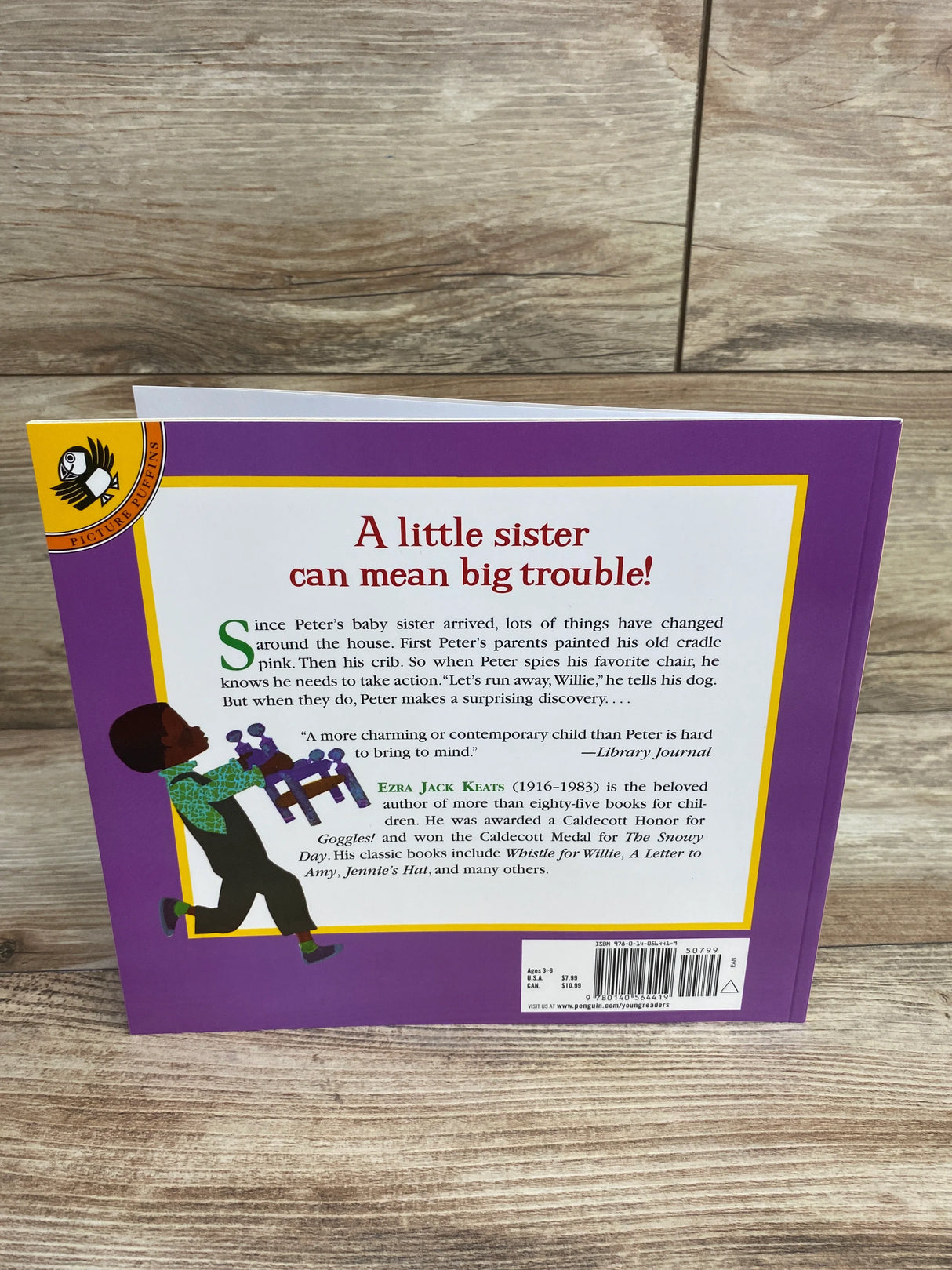 Back cover of a children's book with purple border showing text about a boy Peter and his baby sister, author Ezra Jack Keats, and a cartoon boy holding a chair