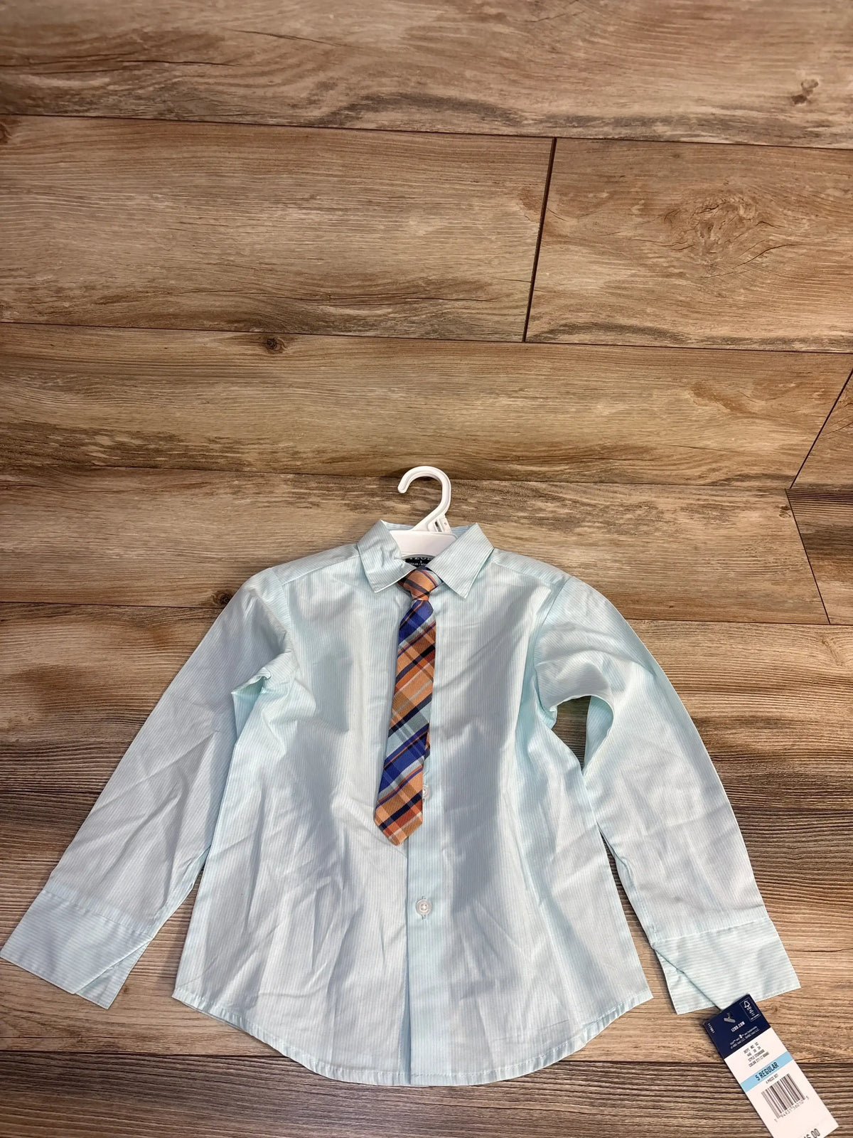 Light blue striped kids dress shirt with orange and blue tie on wooden floor