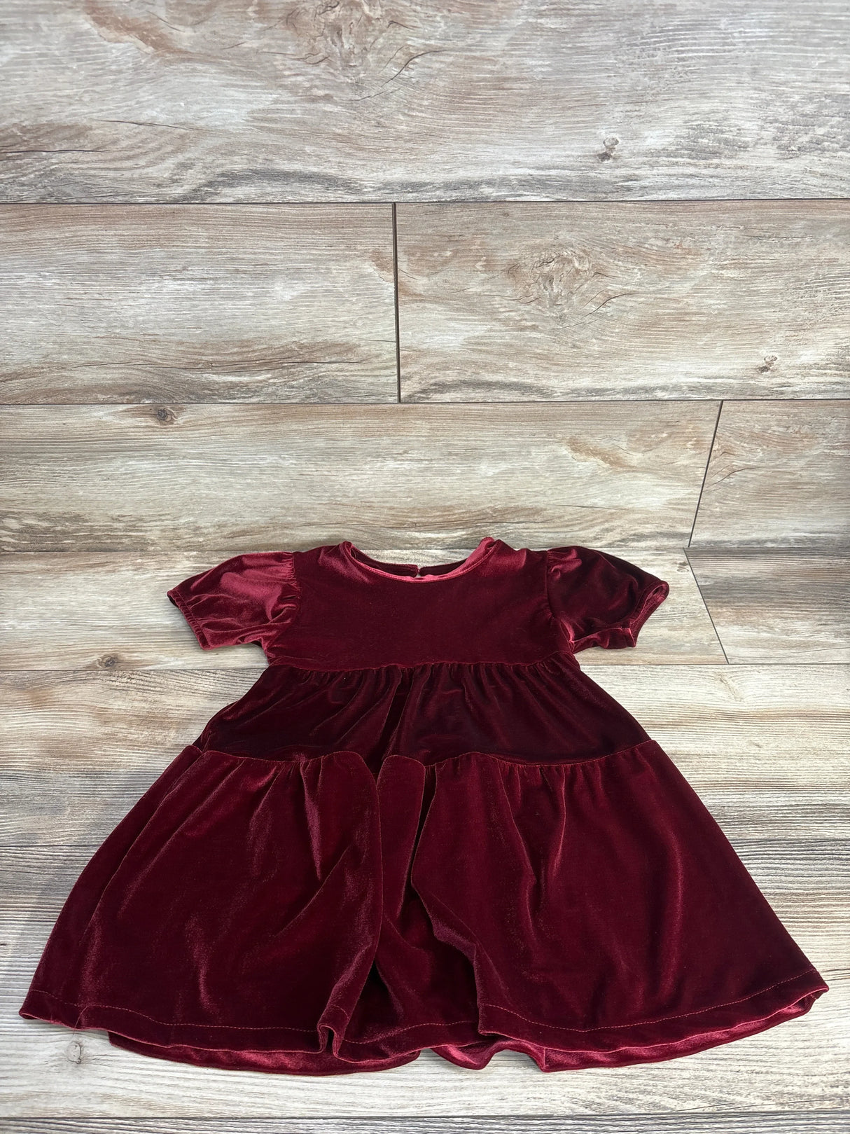 Burgundy velvet short sleeve girls dress on wood background