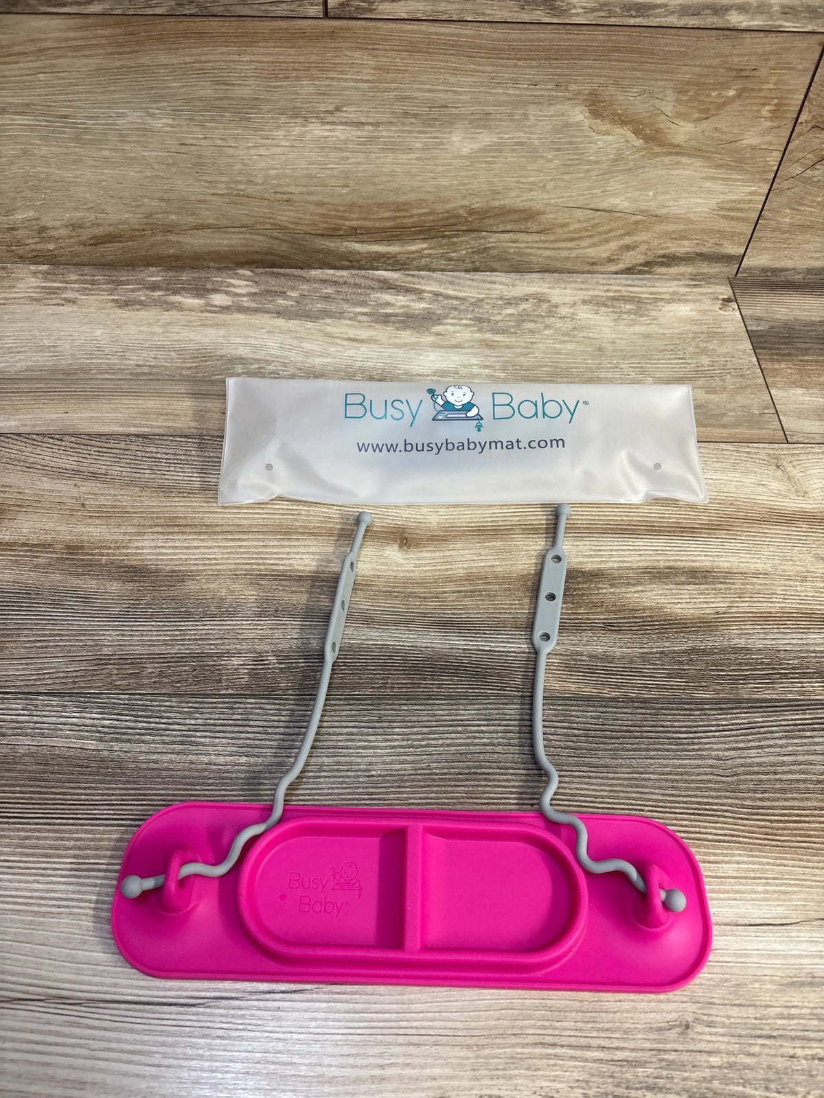Top view of Busy Baby mini mat showing pink silicone tray with divided section and two gray adjustable toy straps
