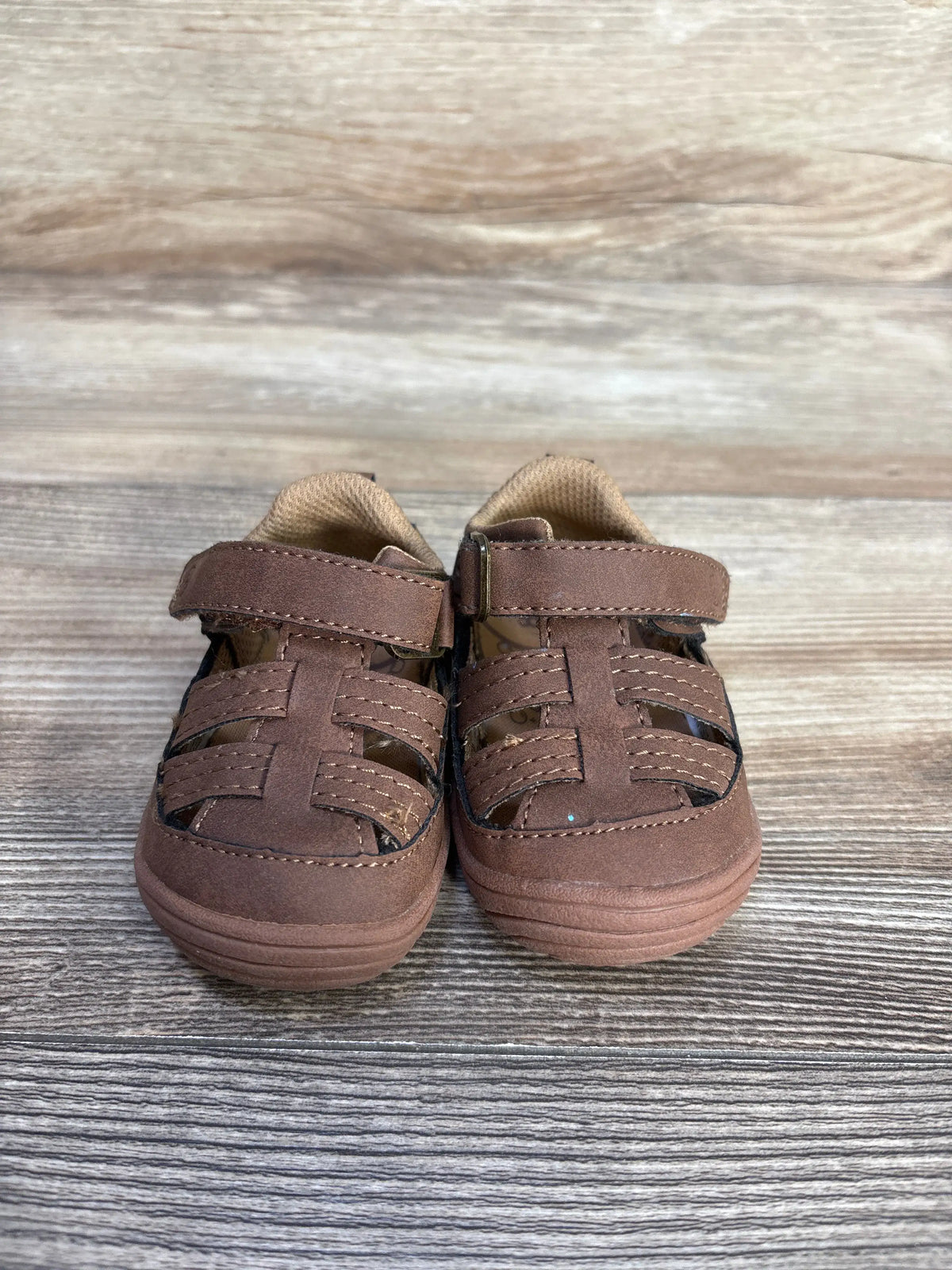 Stride Rite Amos 3.0 brown fisherman sandals for toddlers, size 3c, on a wood background